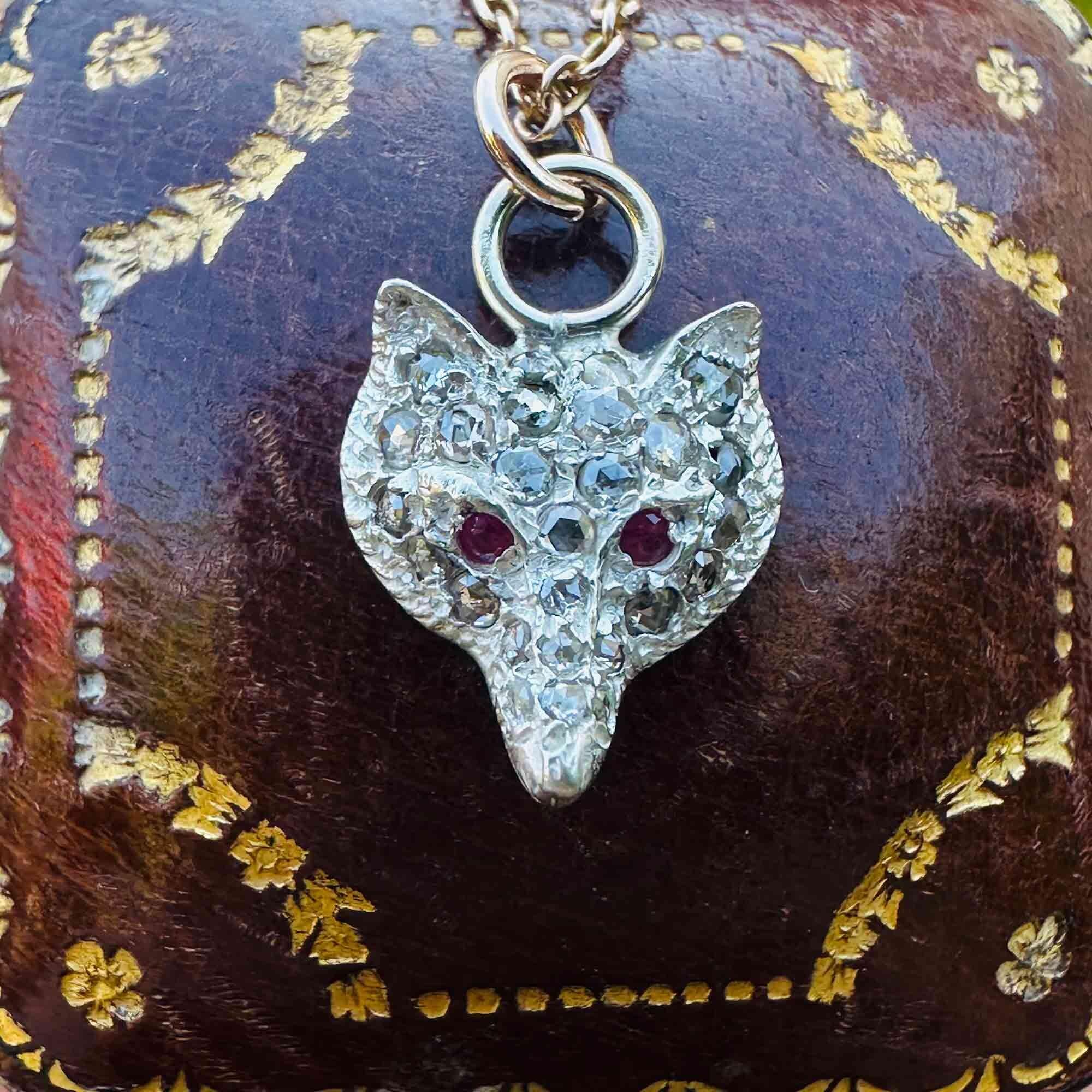 Vintage fox head pendant adorned with rose-cut diamonds in silver, accented by ruby eyes and 9ct rose gold fittings on an antique box.