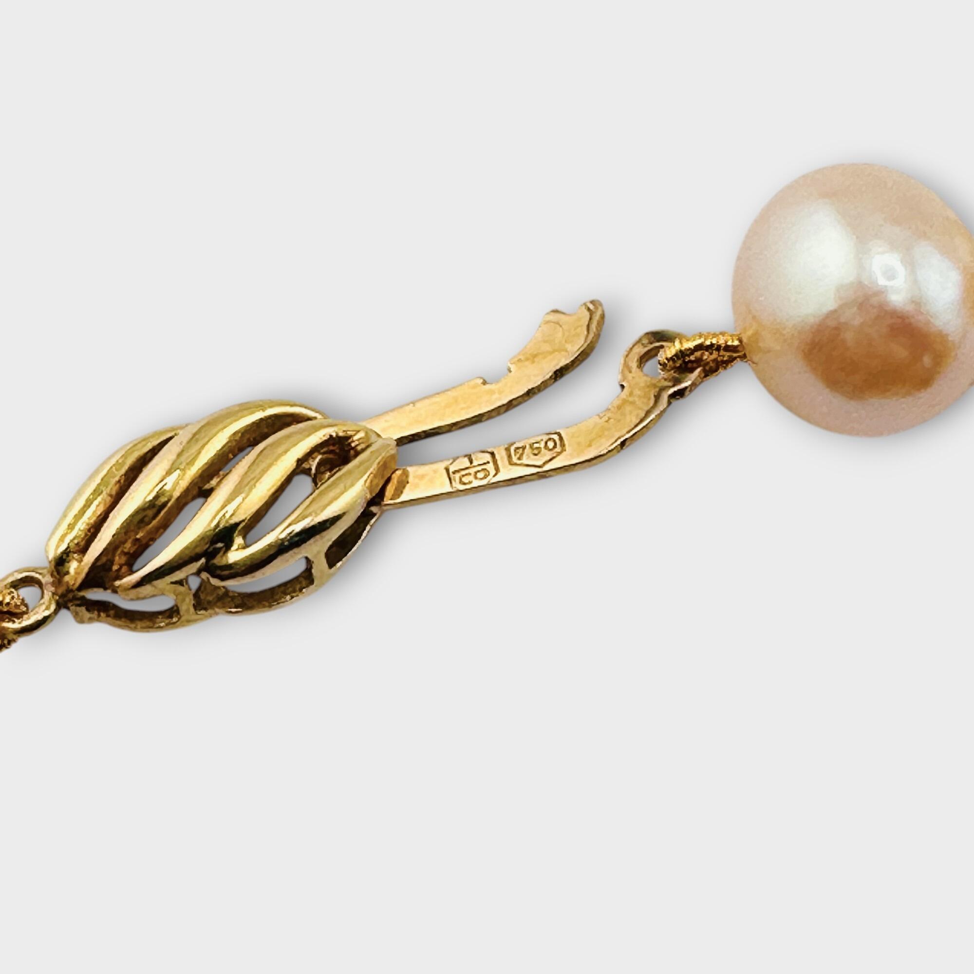 Side view of white pearl necklace with gold fastening detail