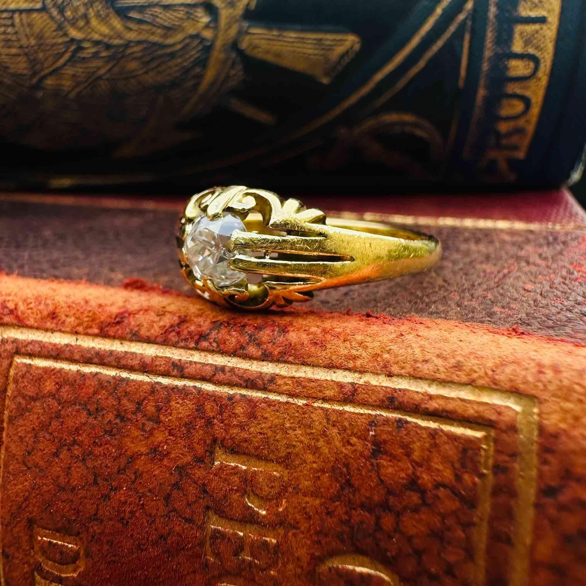 Antique 18k yellow gold old cut diamond gypsy ring on edge of book.