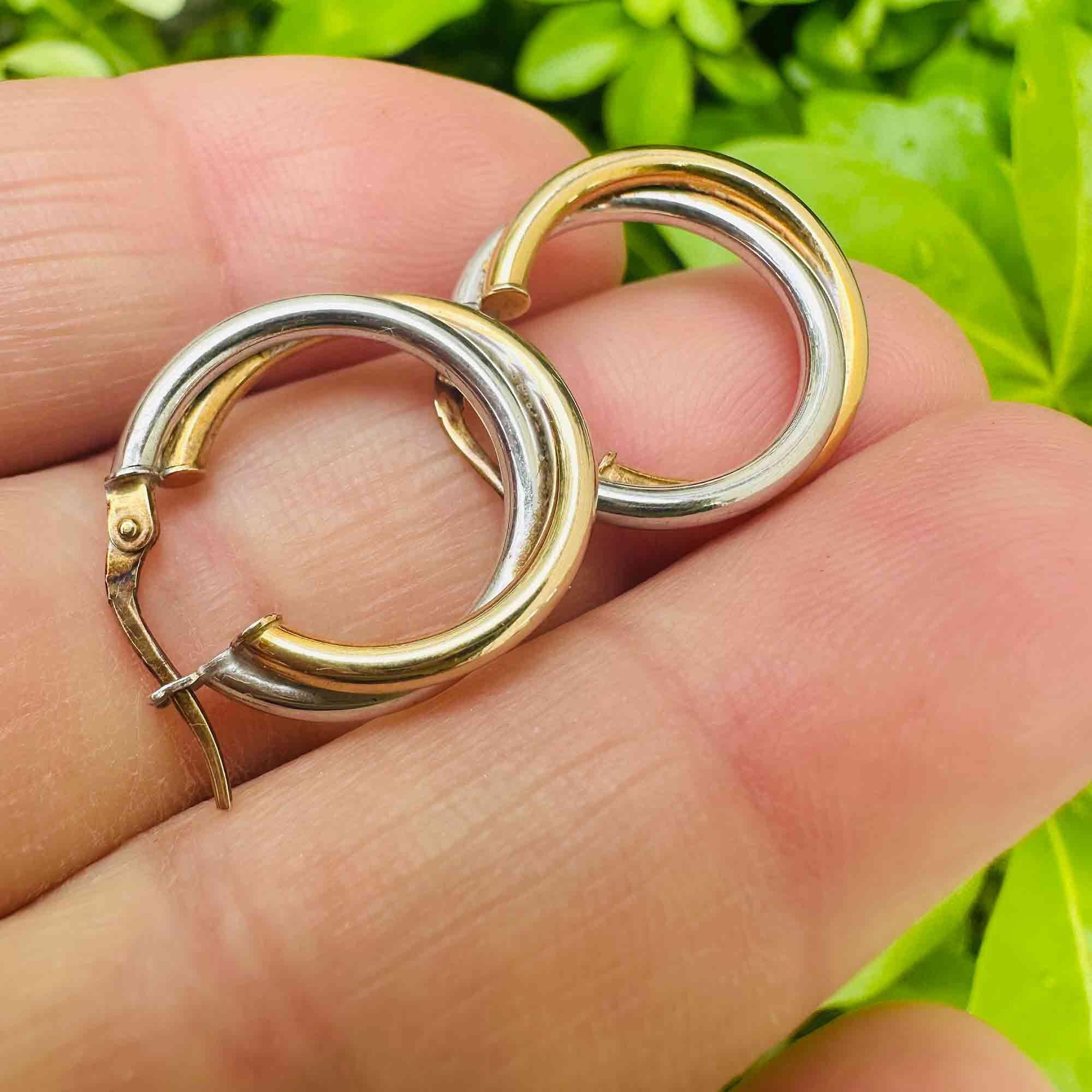 Italian bi-colour 9k gold hoop earrings held in models hand.