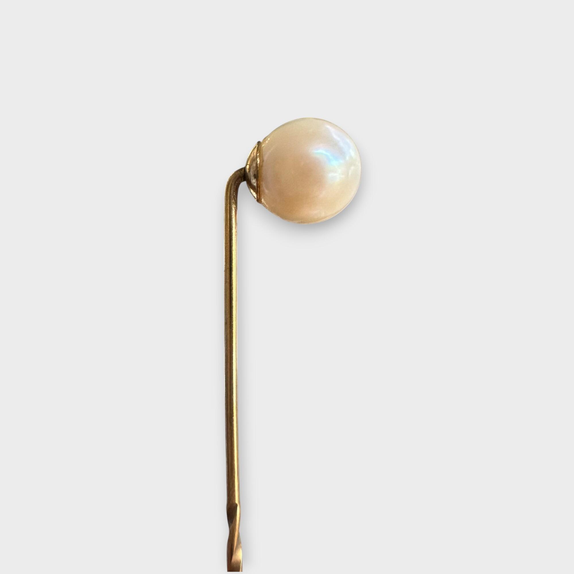 Late Art Deco 9k gold 7mm Cultured Saltwater pearl stick pin on grey background, side view.