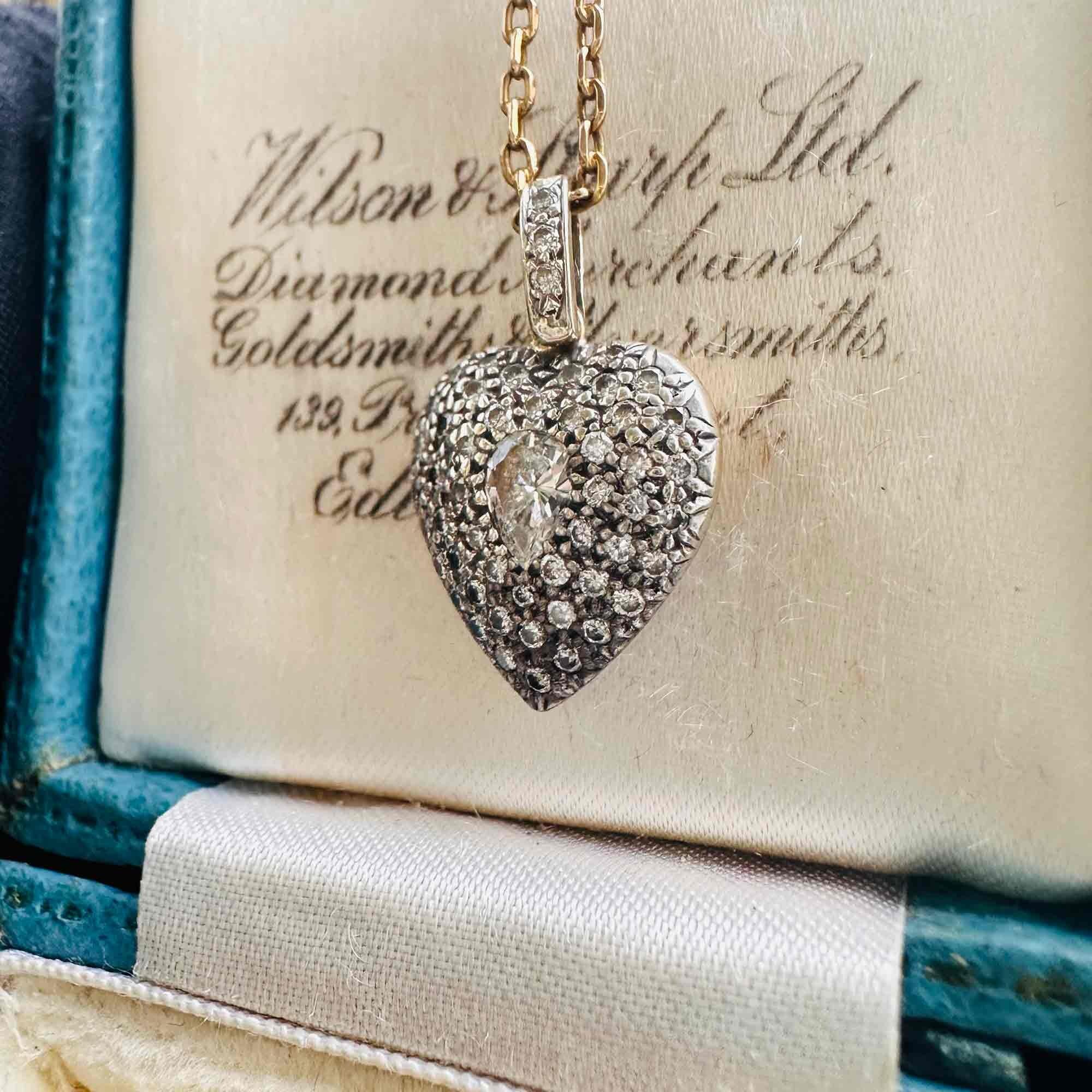 Diamond Heart Locket Pendant with Pear-Shaped Center displayed on a antique box