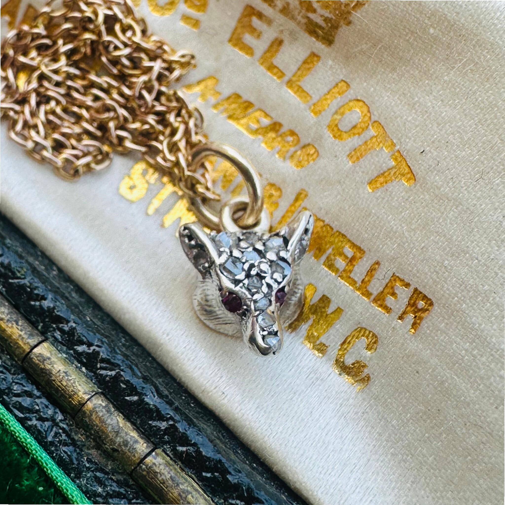 Victorian Diamond & Ruby Eyes Fox Pendant displayed laying on antique box