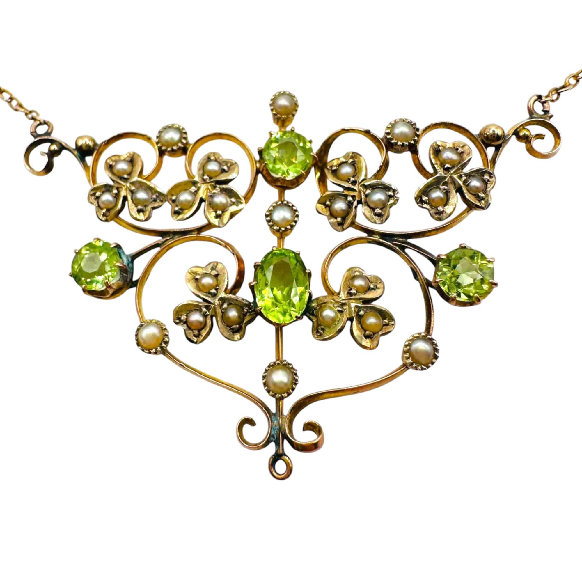 Front view of Art Nouveau 9ct gold lavalier necklace with scrollwork, four peridot gemstones, and seed pearl foliate motif