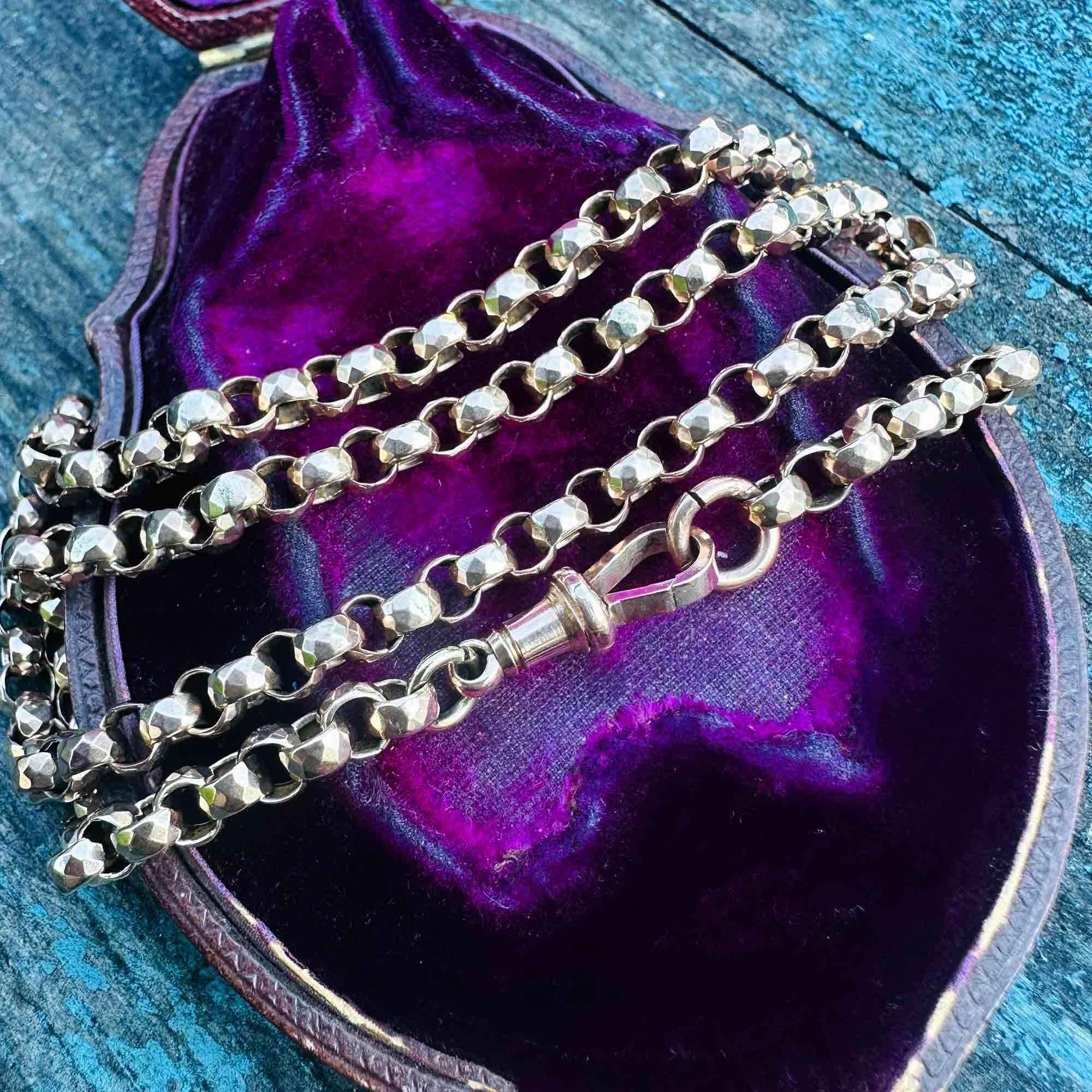 Antique 9k rose gold chain necklace with faceted belcher links, ending in an original Victorian dog clip clasp on purple velvet box with turquoise background.