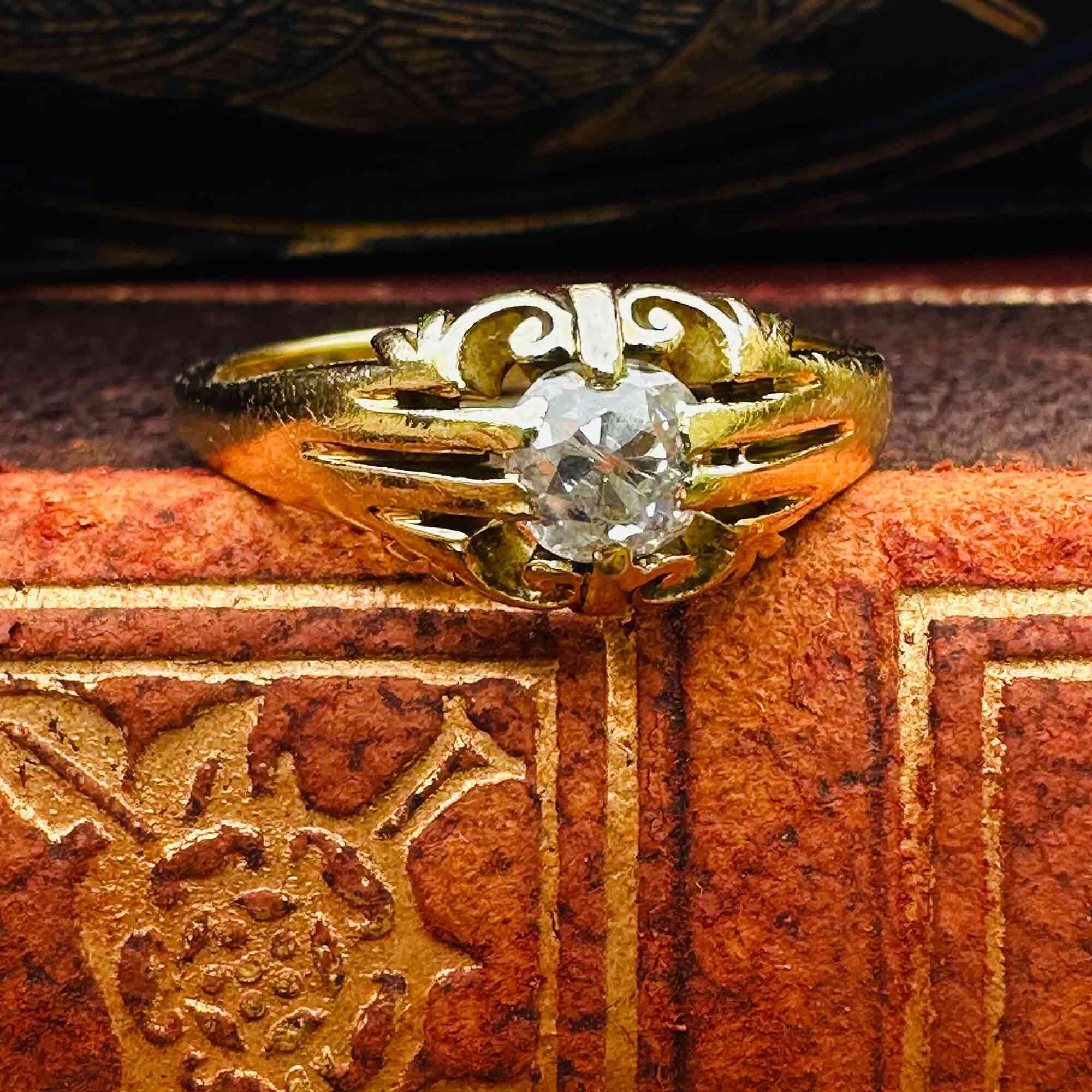 Antique 18k yellow gold old cut diamond gypsy ring on edge of book.