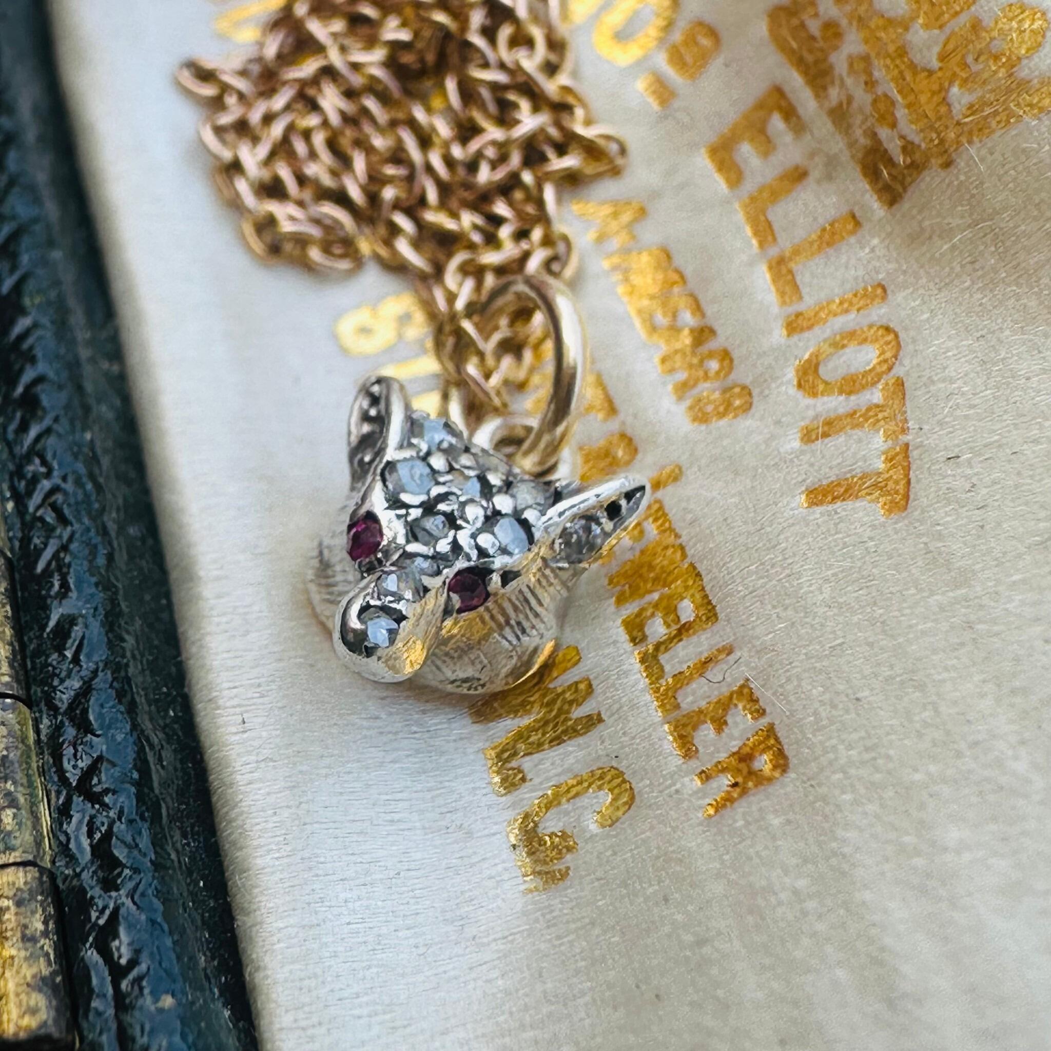 side view of Victorian Diamond & Ruby Eyes Fox Pendant displayed laying on antique box