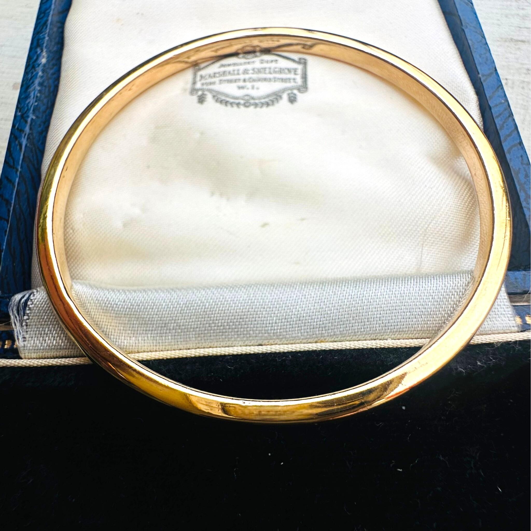 side profile of Vintage Solid Gold Bangle displayed laying on an antique box