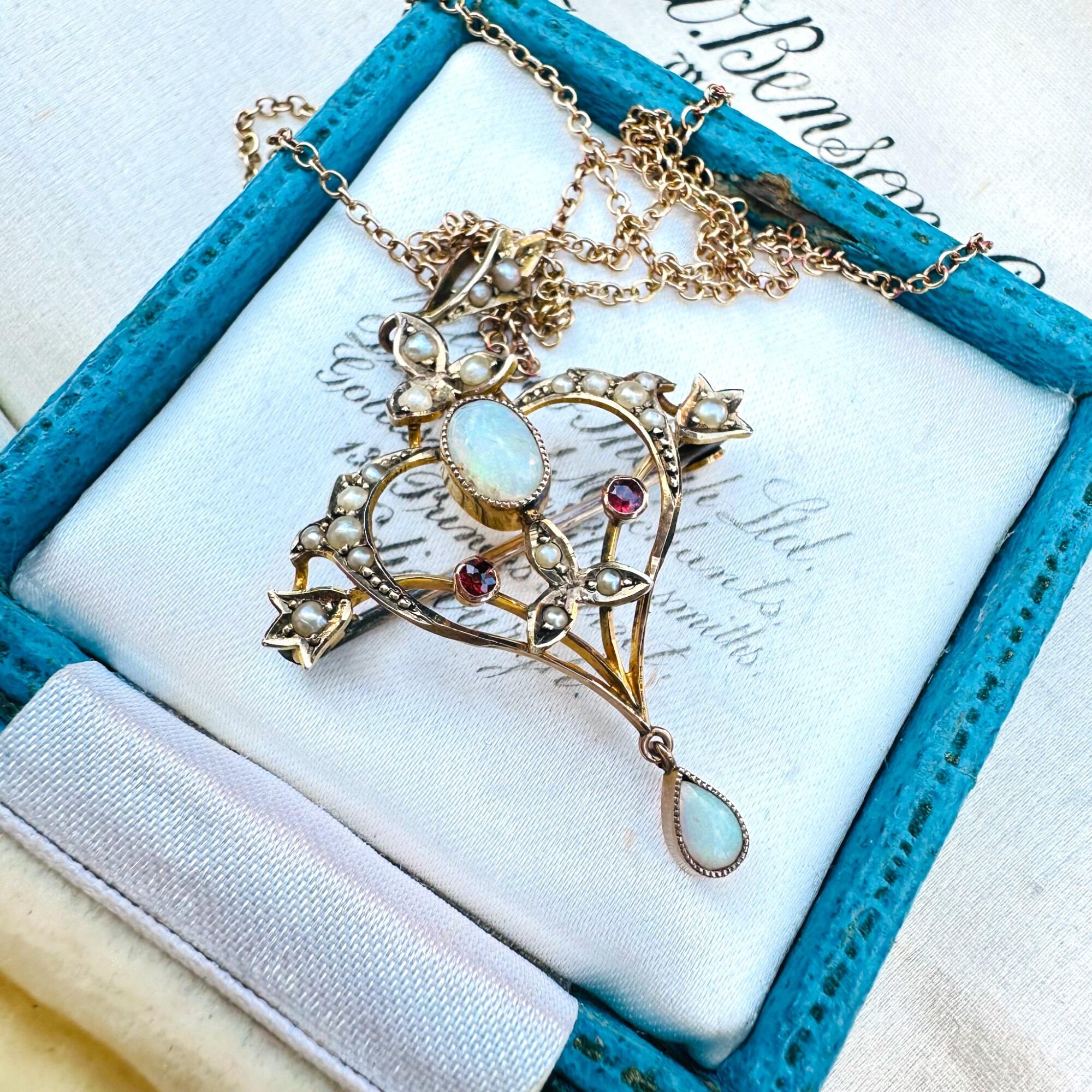 Close-up of antique heart-shaped pendant with glowing oval opal, seed pearls, and ruby accents in 9k gold – p343