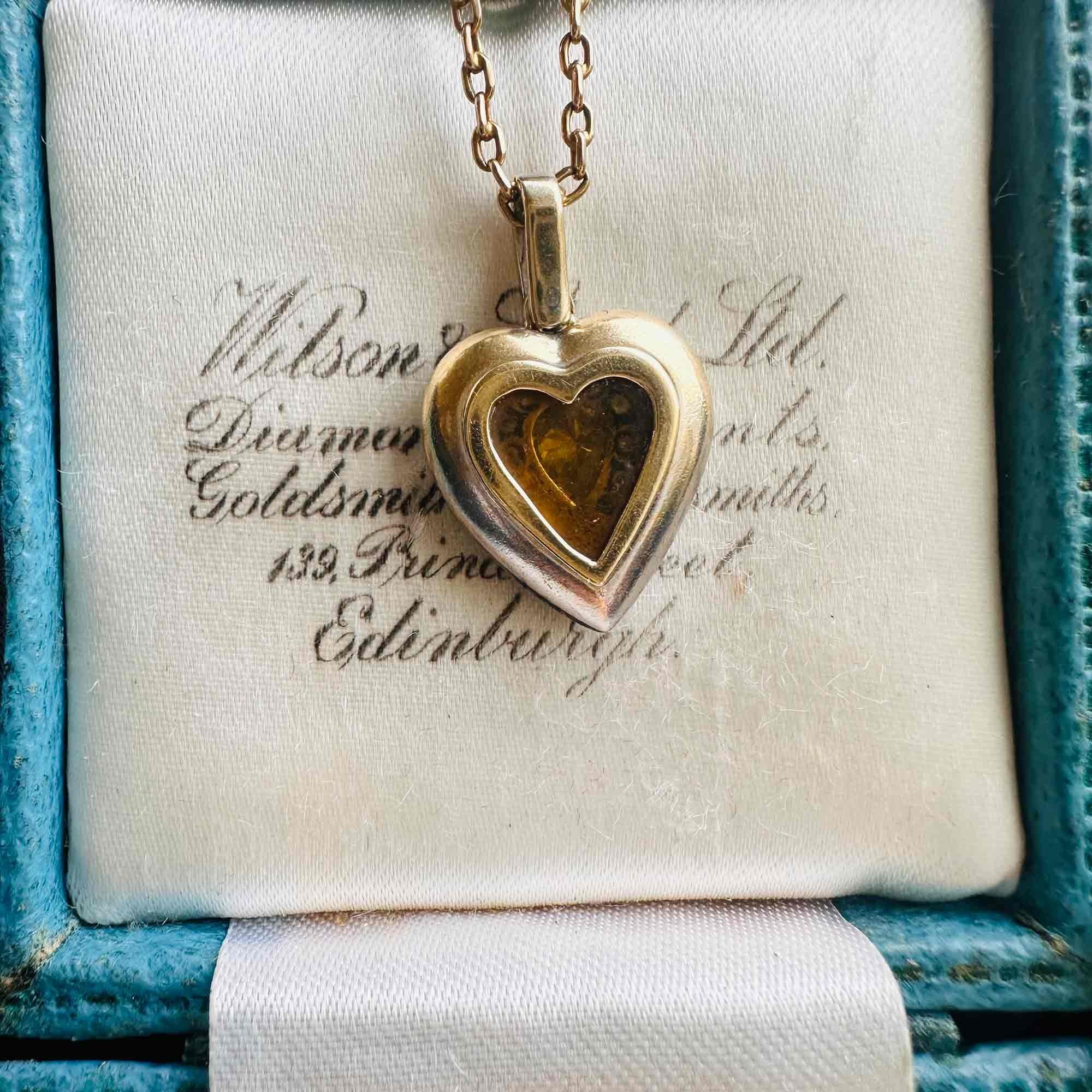 Diamond Heart Locket Pendant with Pear-Shaped Center displayed on a antique box