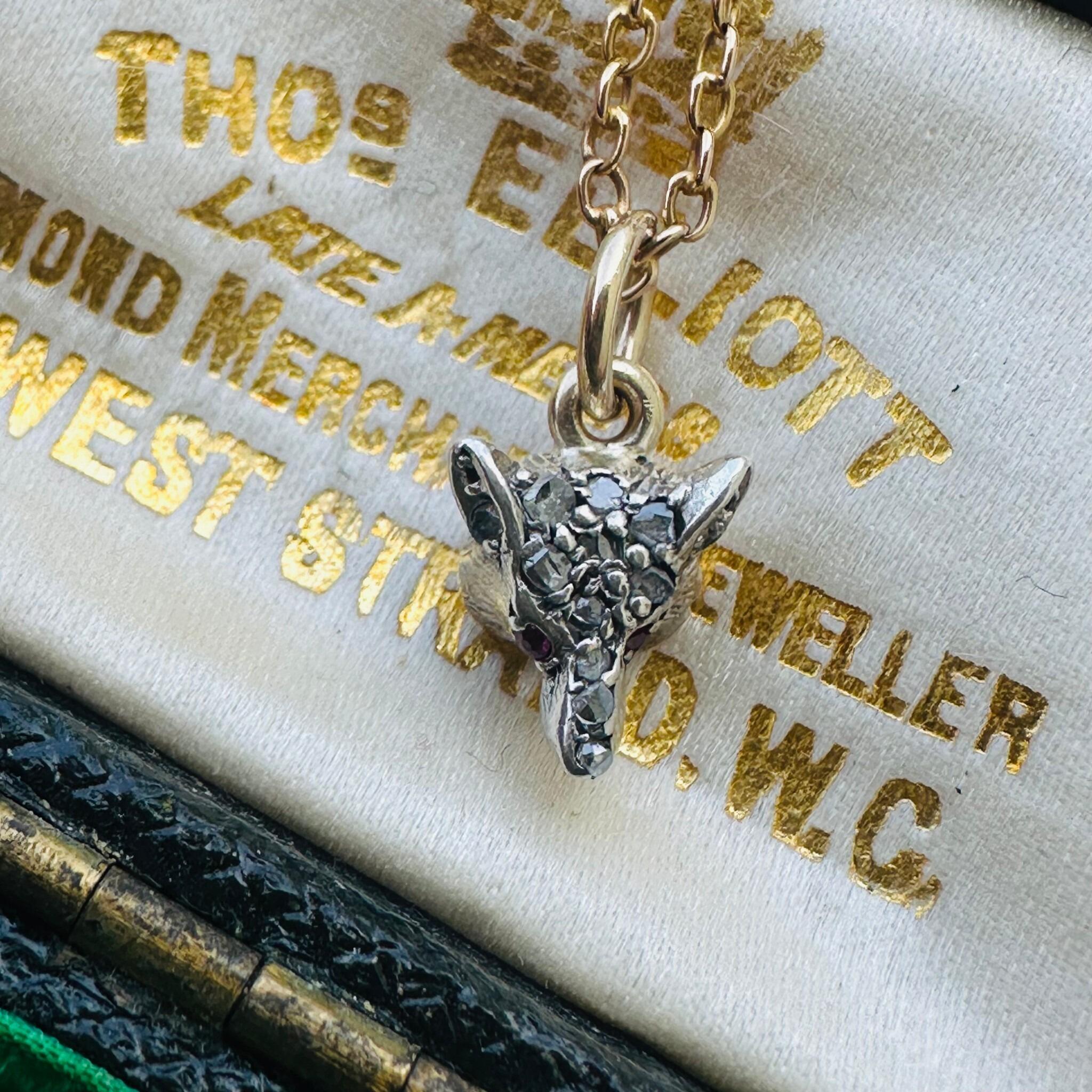 Victorian Diamond & Ruby Eyes Fox Pendant displayed laying on antique box