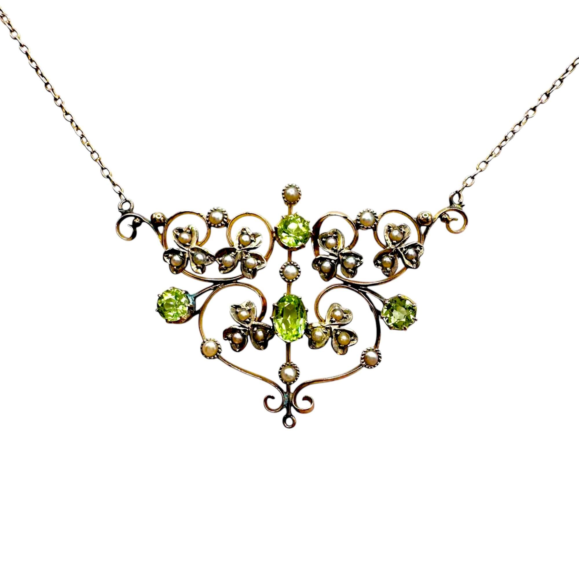 Front view of Art Nouveau 9ct gold lavalier necklace with scrollwork, four peridot gemstones, and seed pearl foliate motif