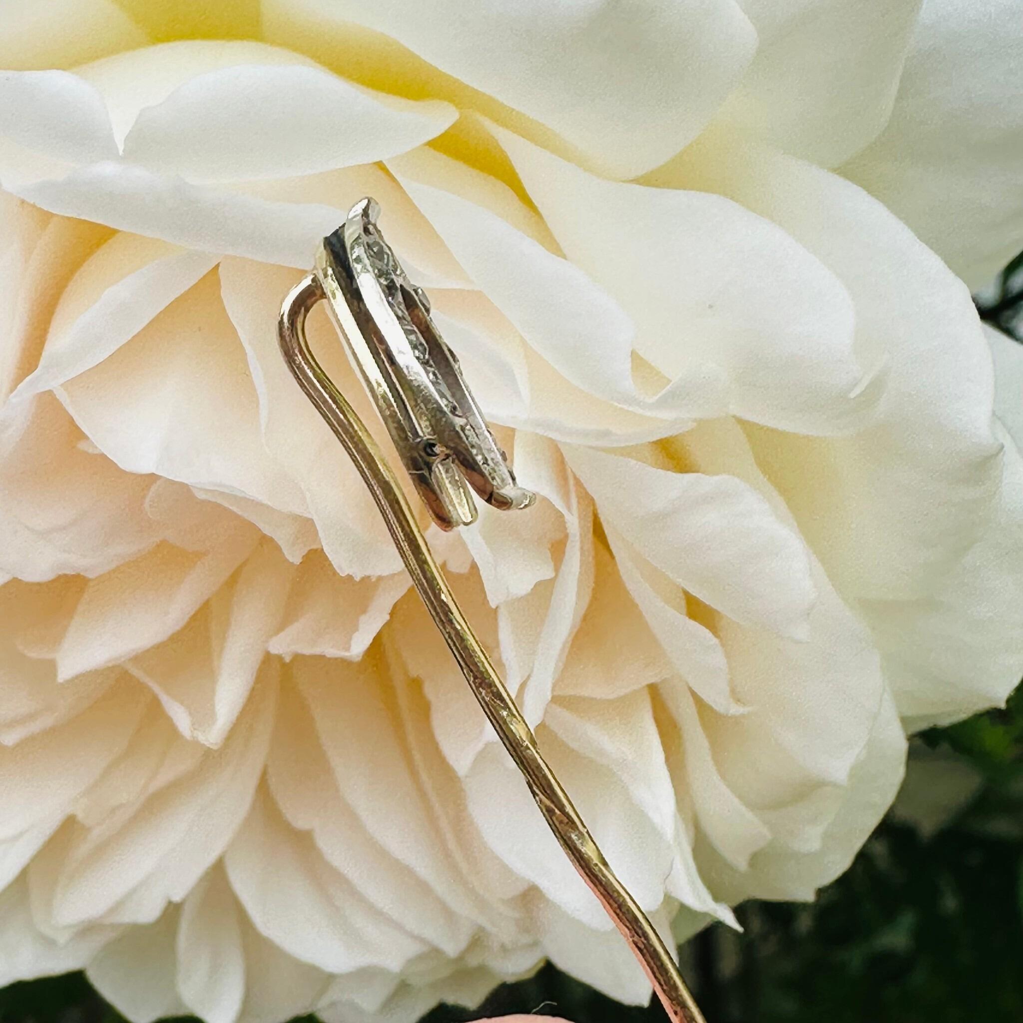 side profile of Antique Diamond Horseshoe Stick Pin with cream flower background