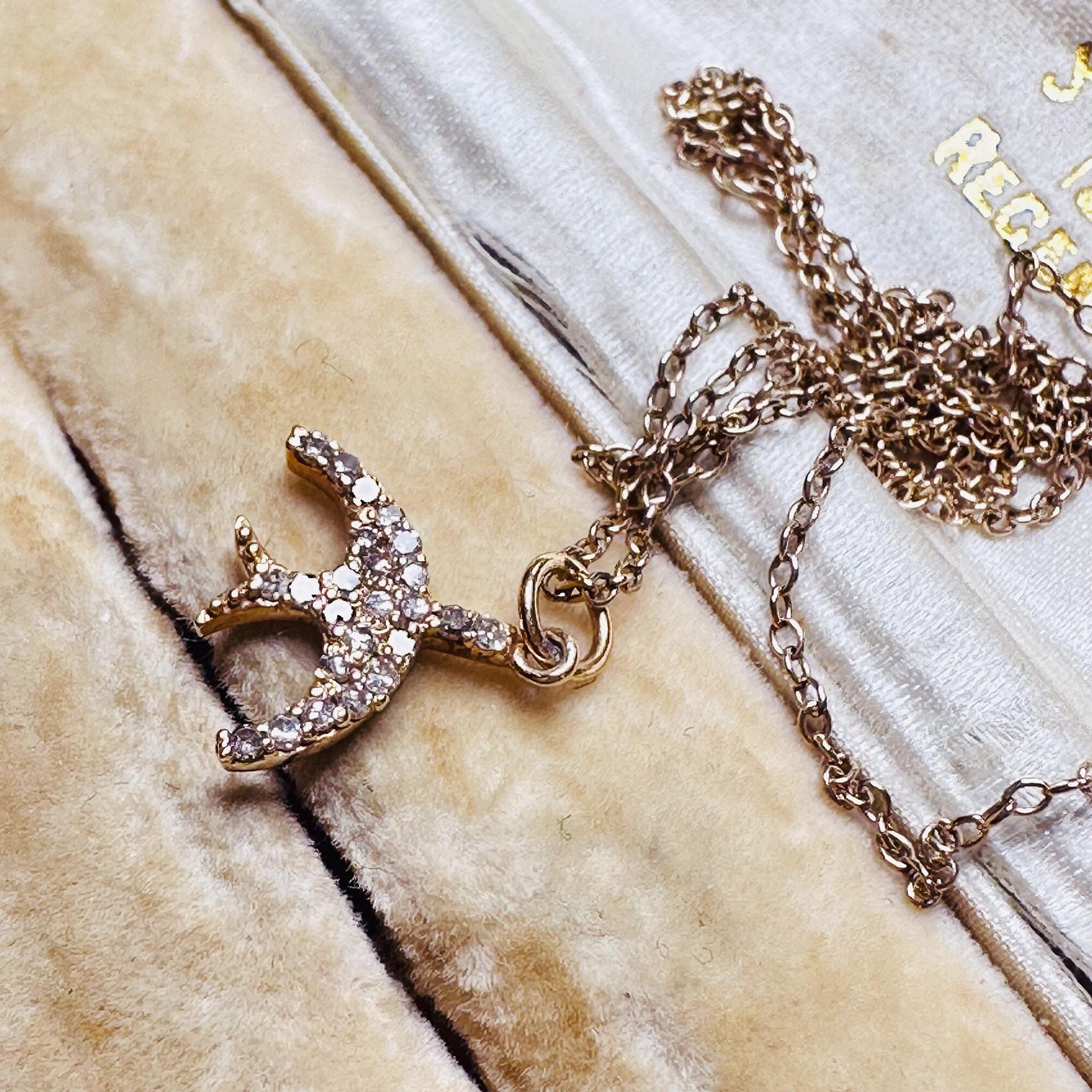 14ct Rose Gold & Diamond Swallow Charm Pendant with chain laying on antique box.