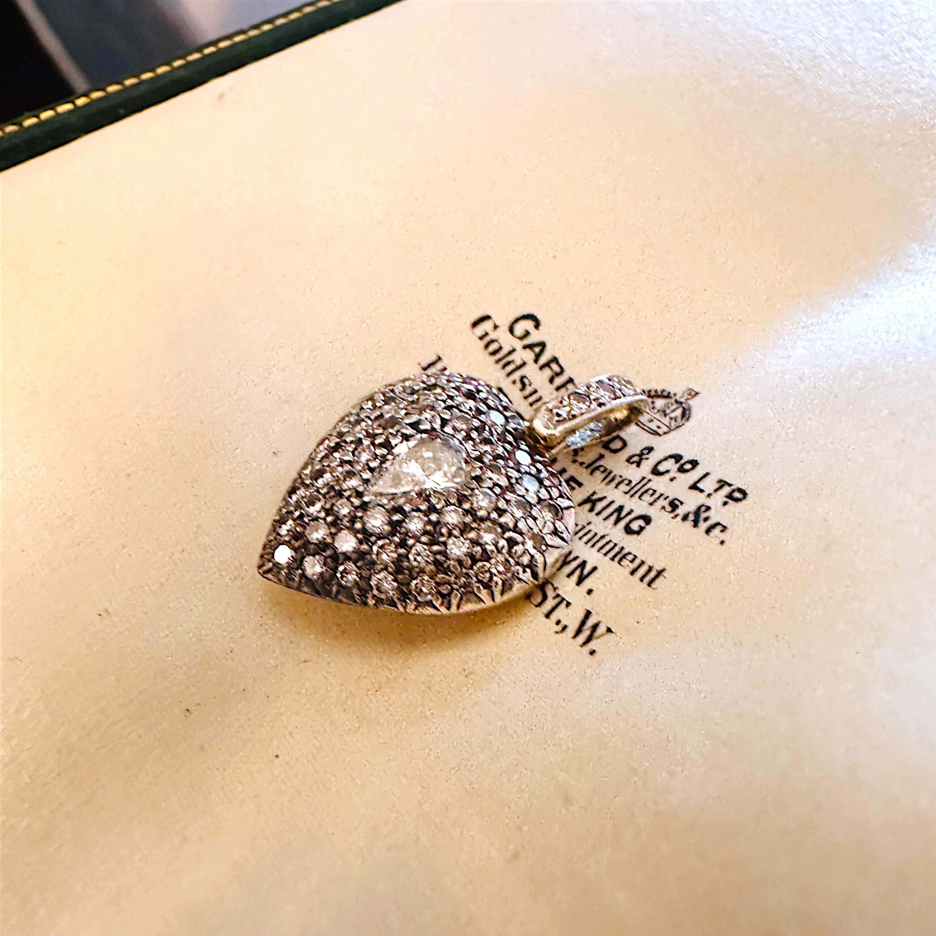 Diamond Heart Locket Pendant with Pear-Shaped Center displayed on a antique box