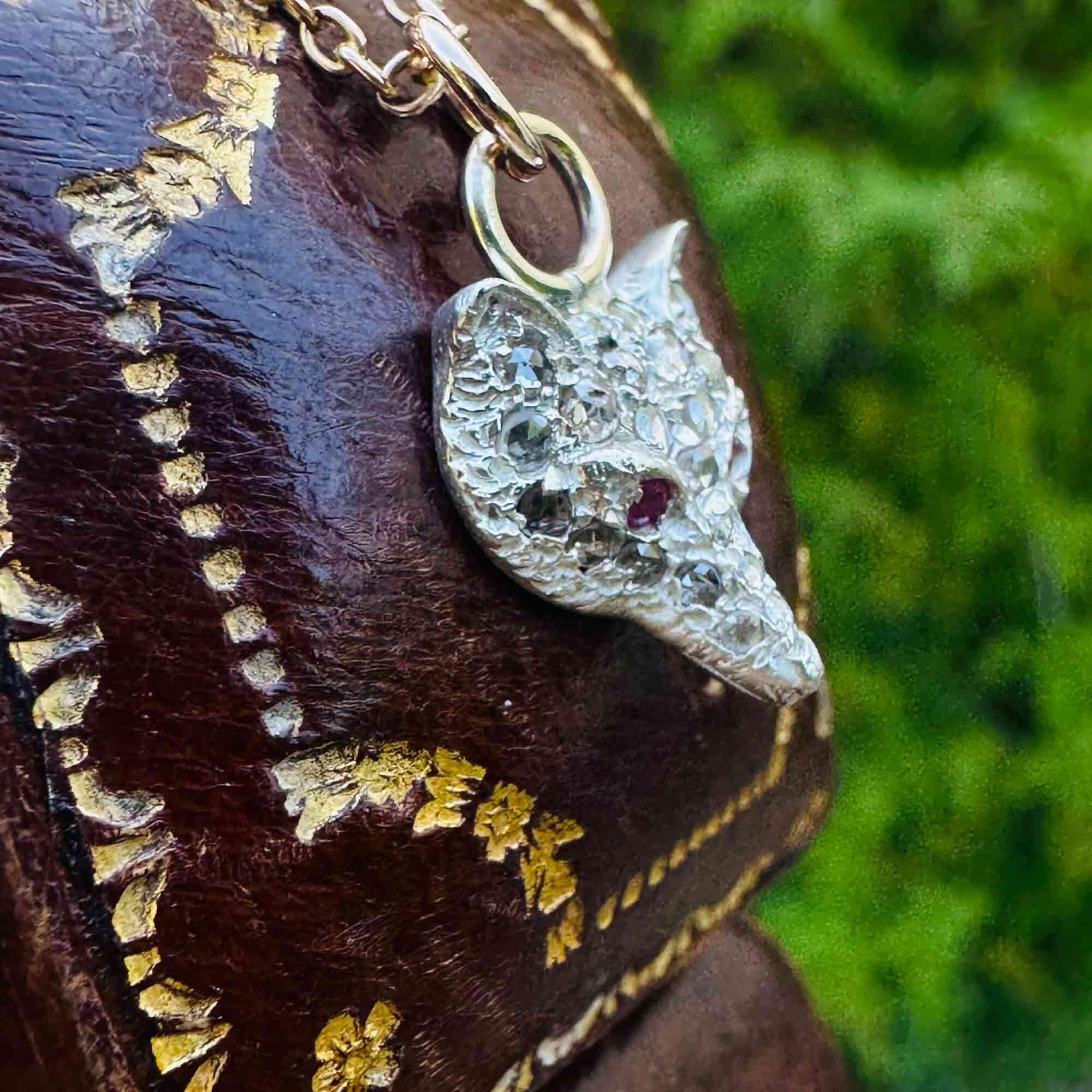 side view of Vintage Fox Head Pendant: Rose Cut Diamonds, Ruby Eyes, Silver & 9ct Rose Gold with antique box in the background