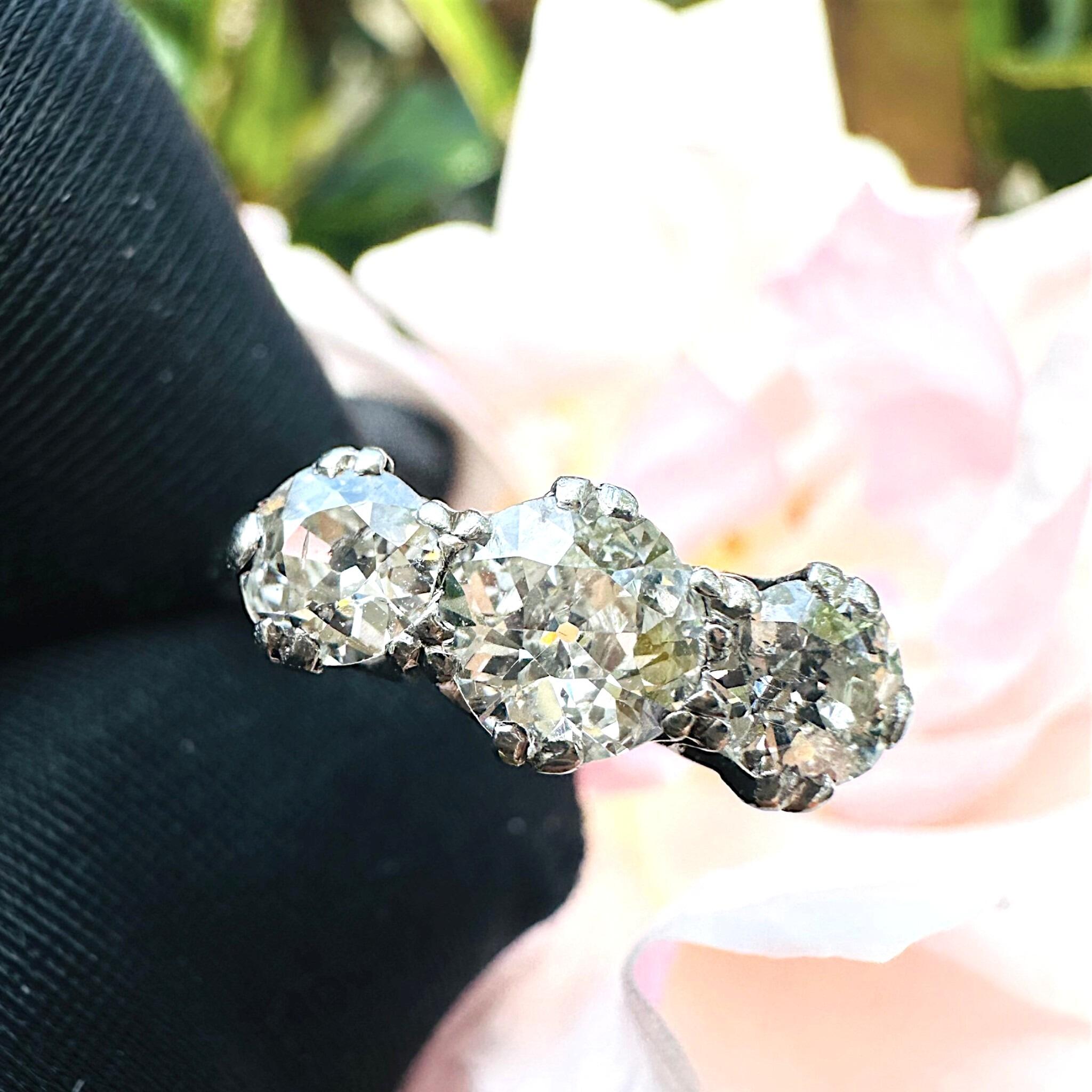 front view of Antique Art Deco18K White Gold & Platinum, Old European Cut Diamond Trilogy Ring with garden background