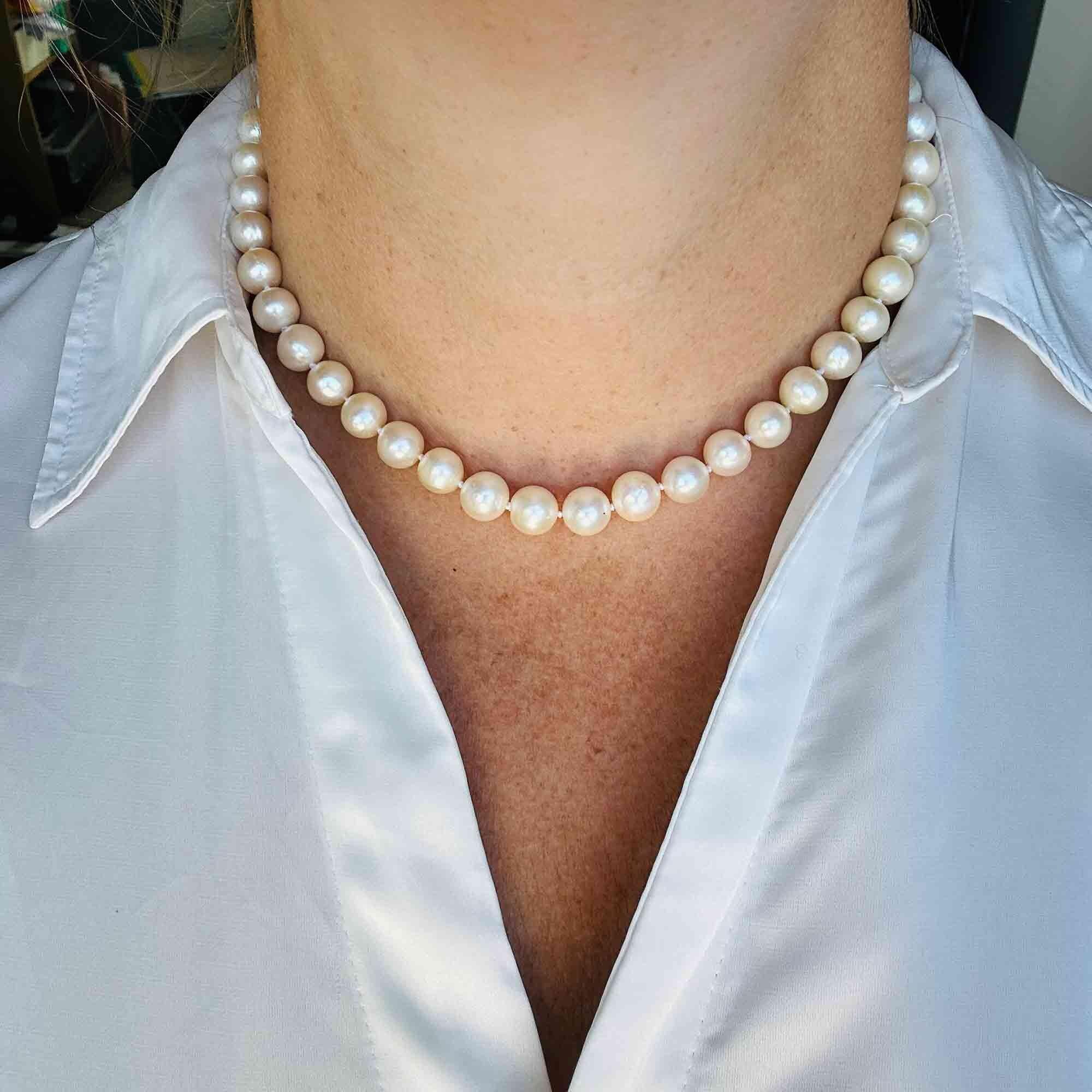 Classic white pearl necklace for bridal or formal wear with 18K clasp, displayed around models neck.