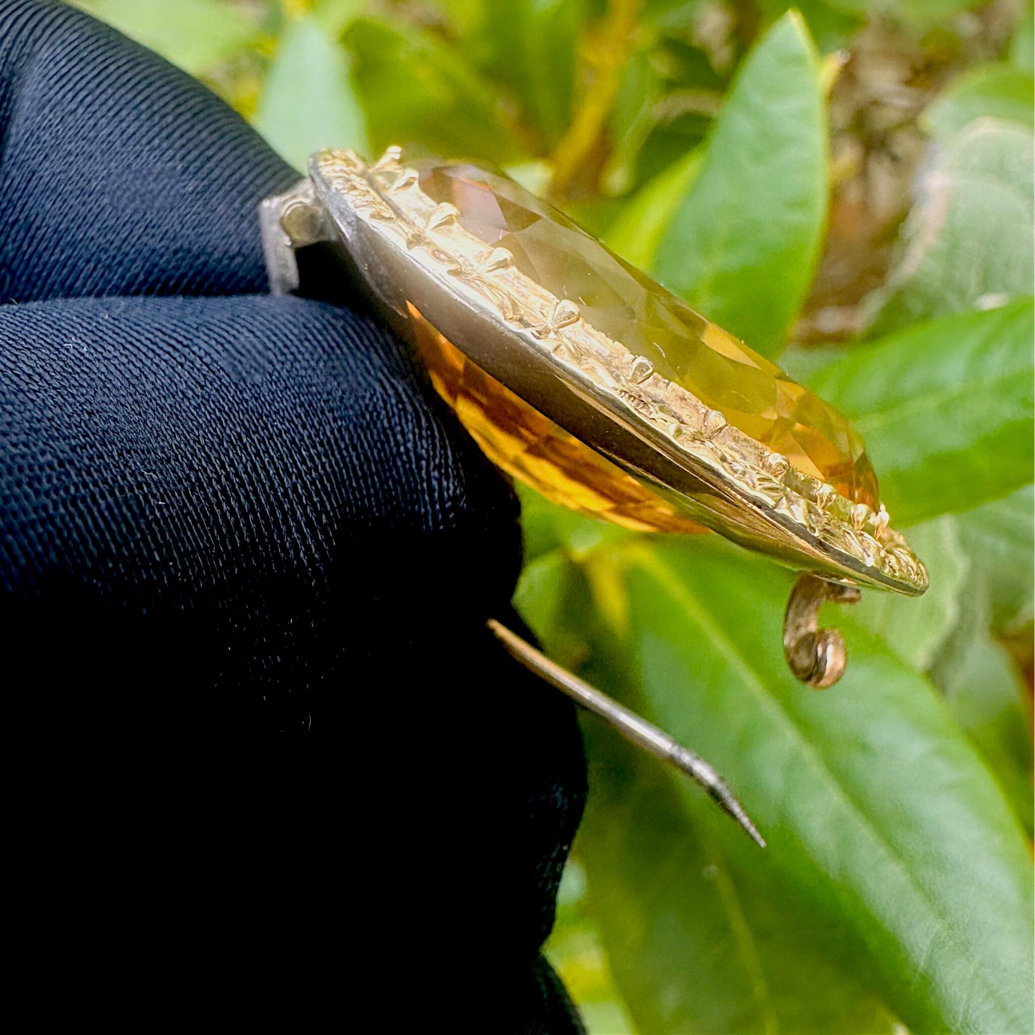 Side profile 15k Gold large Citrine Brooch, held in gloved hand in the garden