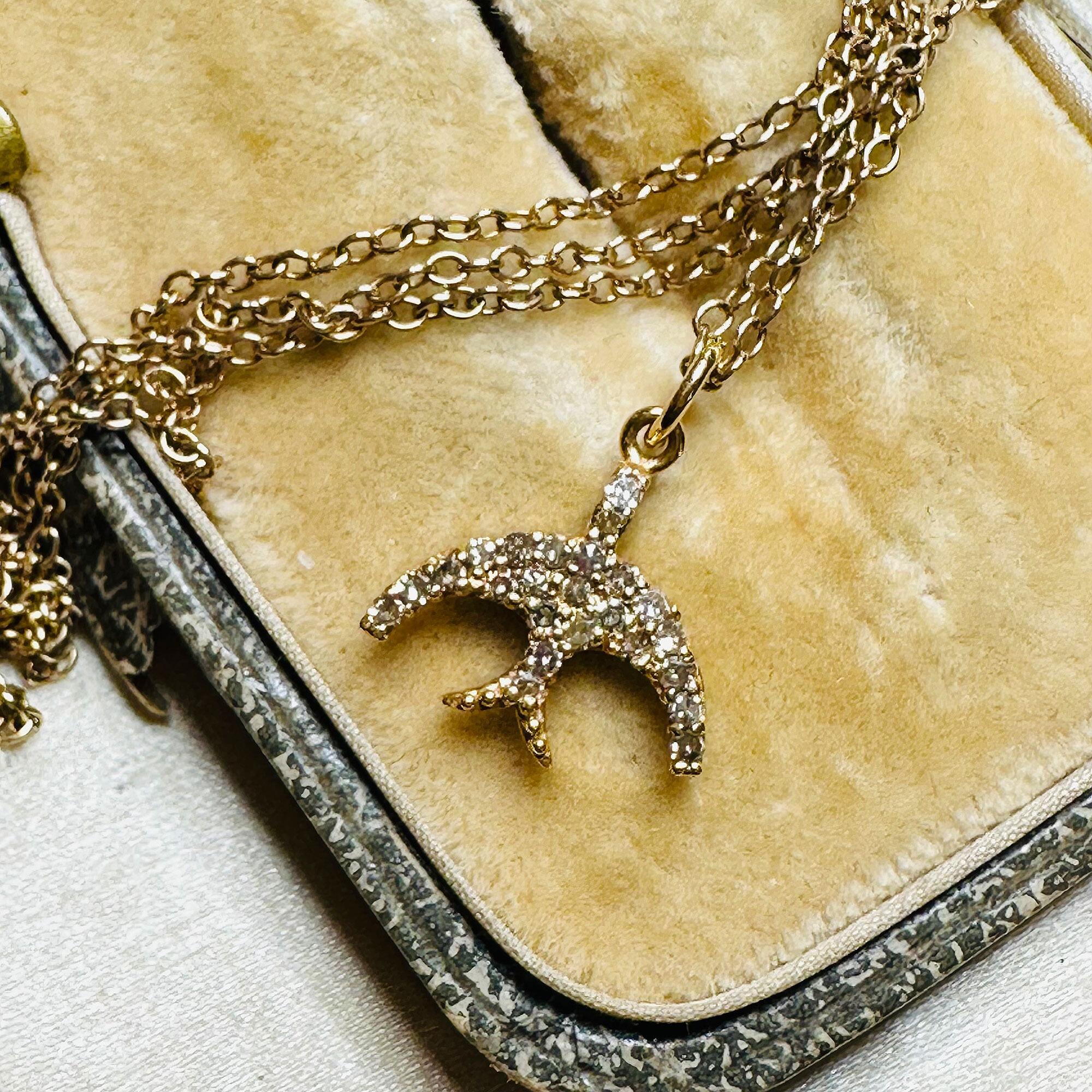 14ct Rose Gold & Diamond Swallow Charm Pendant with chain laying on antique box.