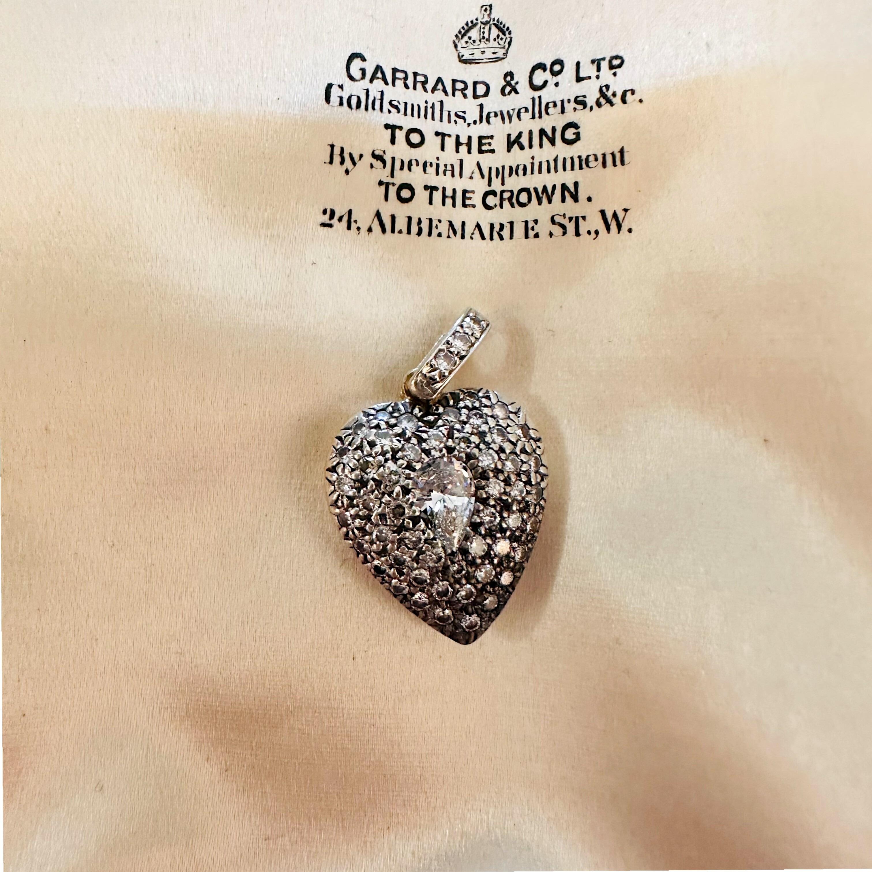 Diamond Heart Locket Pendant with Pear-Shaped Center displayed on a antique box