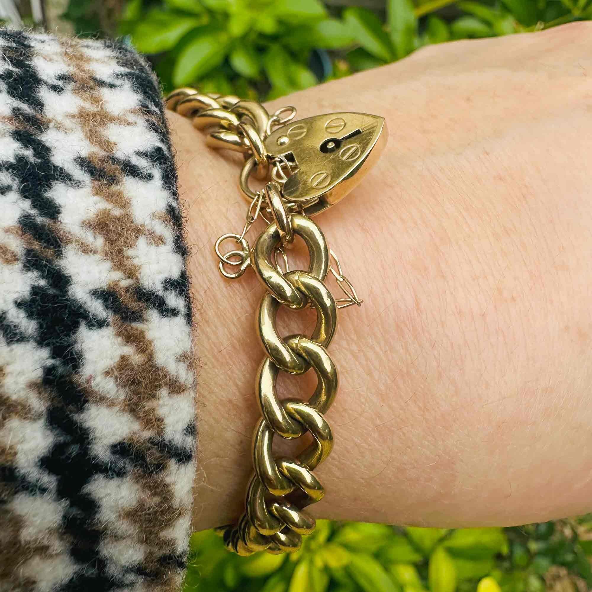 Heavy, Chunky Gold Curb Bracelet & Heart Padlock worn on models wrist in garden