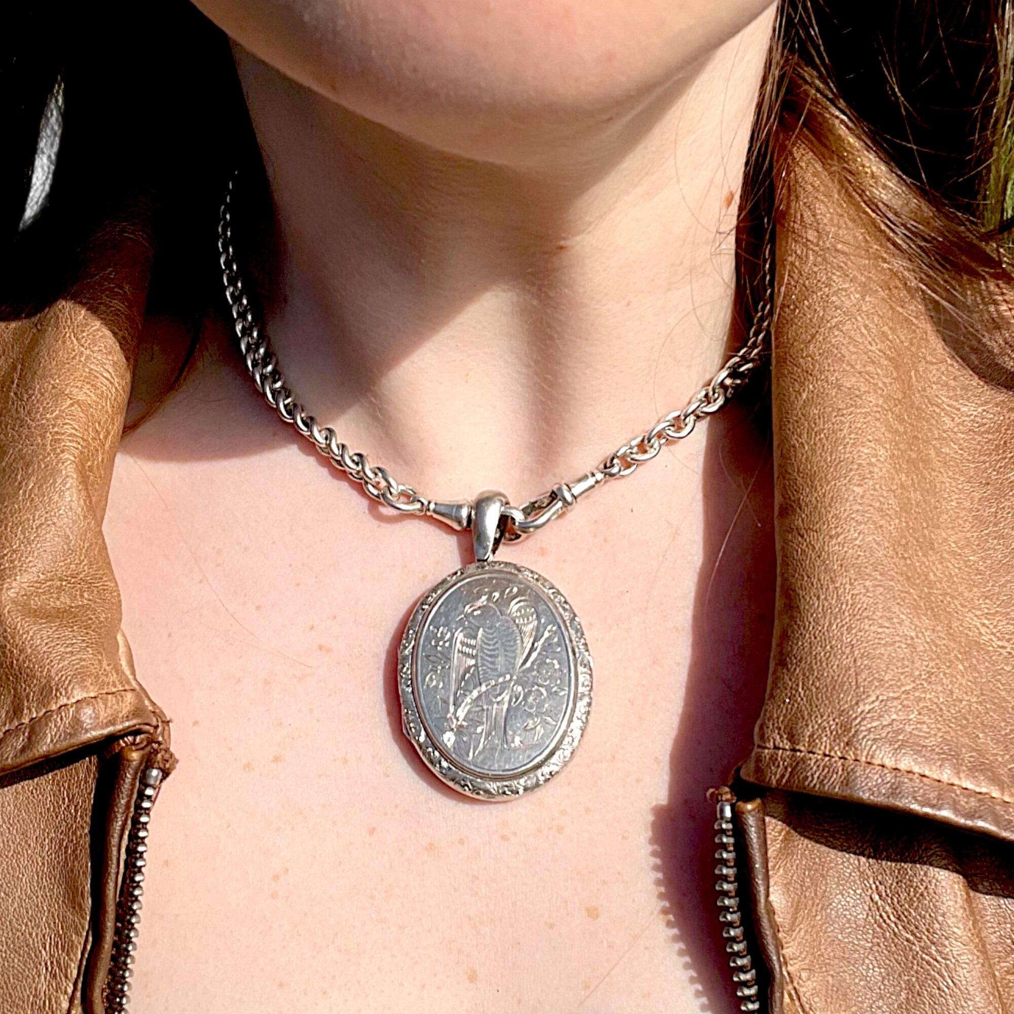 front view of Antique Victorian Silver Engraved Bird Locket Pendant worn on models neck