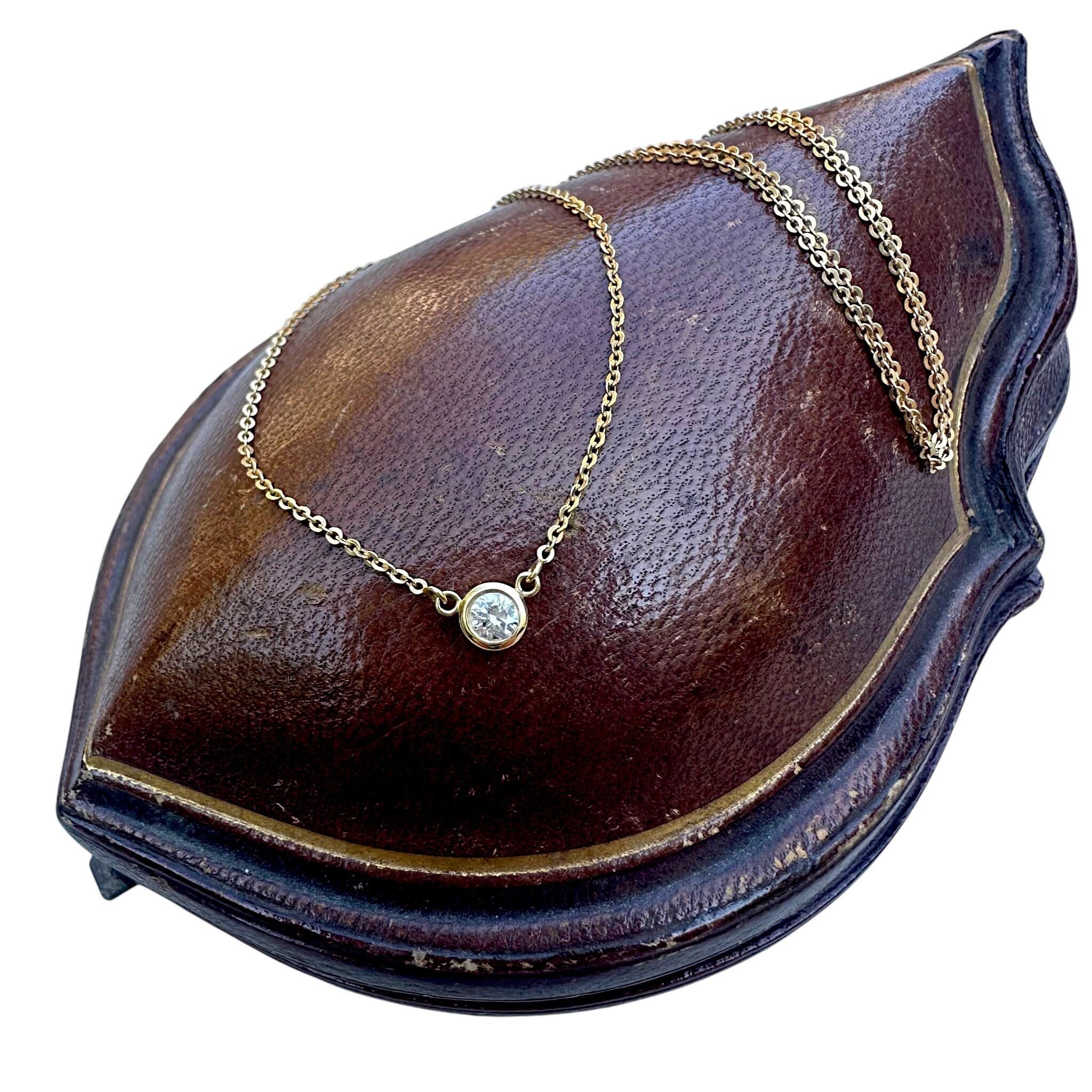 18k Yellow Gold Diamond Bezel Set Pendant Necklace laying over a antique box with white background