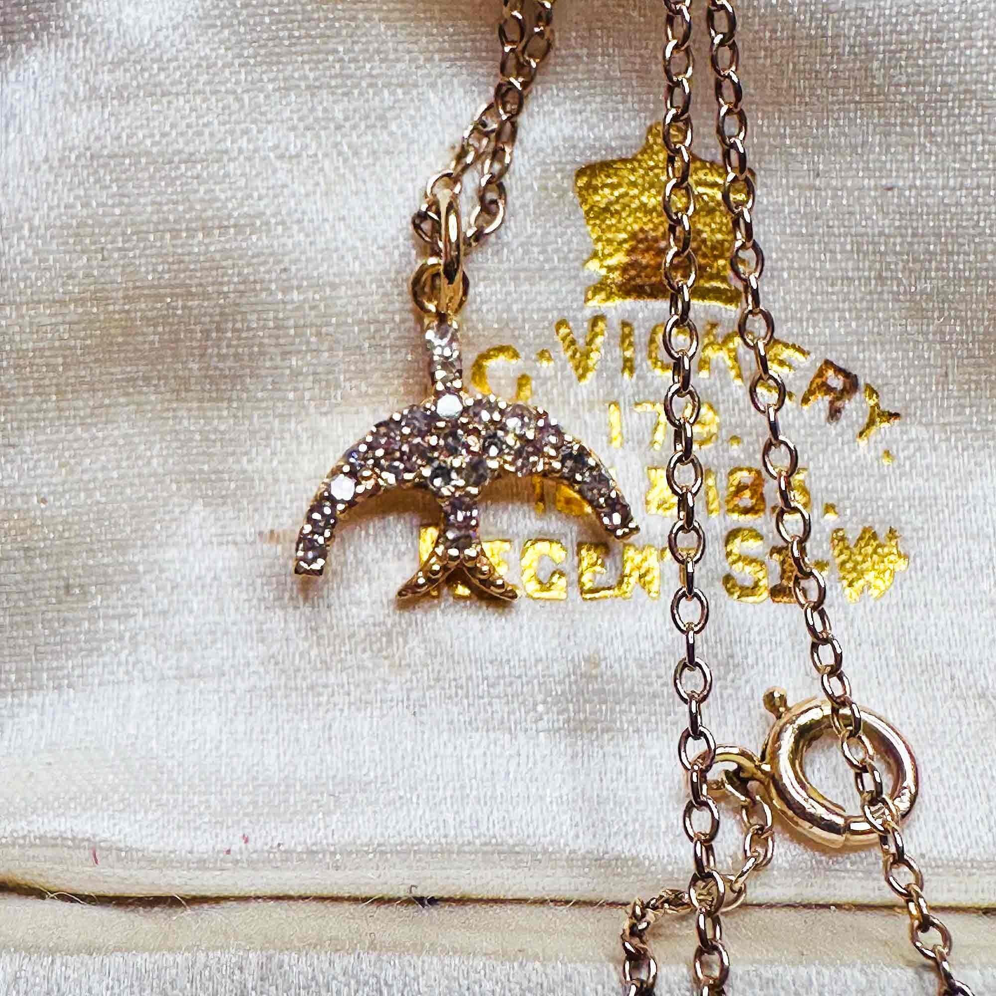 14ct Rose Gold & Diamond Swallow Charm Pendant with chain laying on antique box.