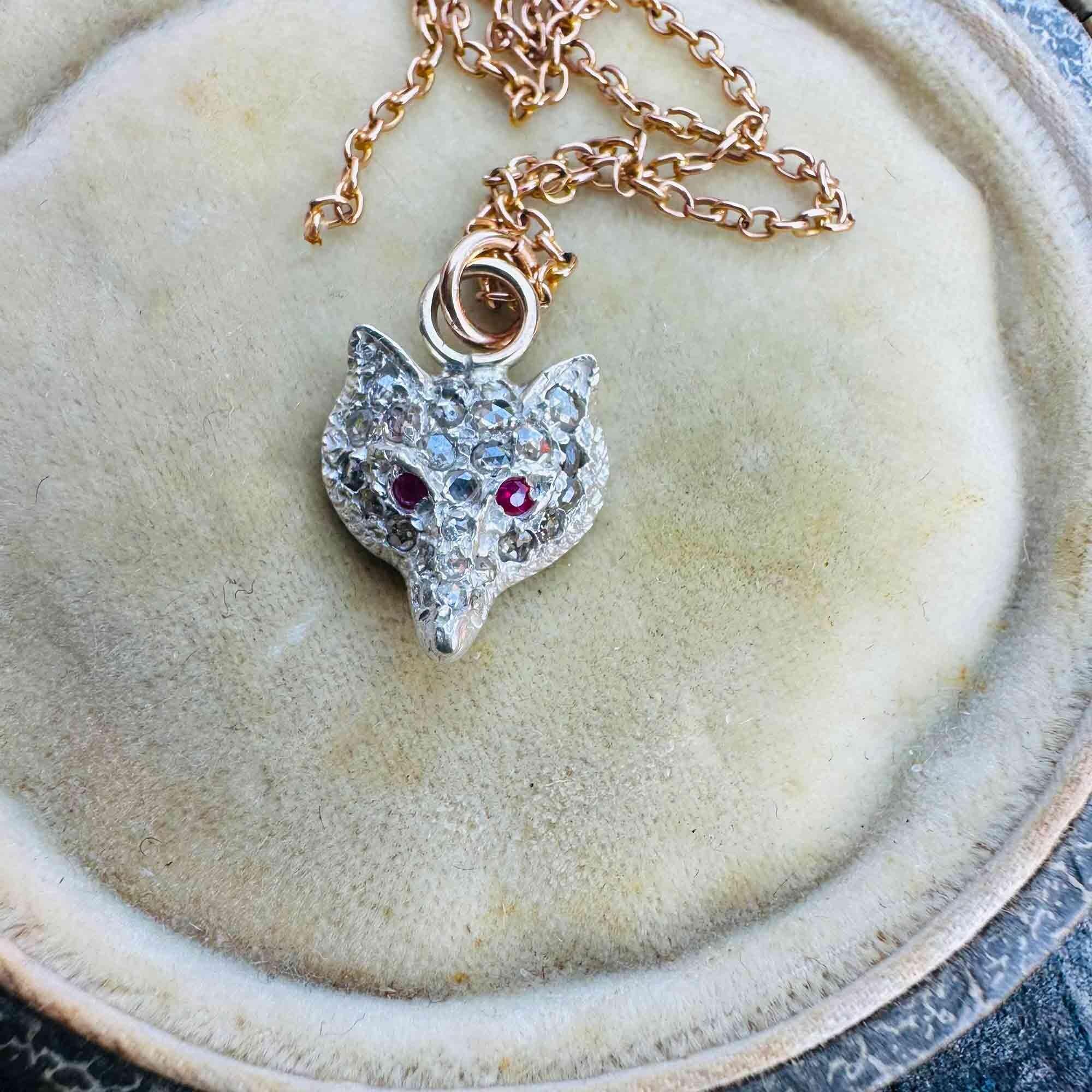 top view of Vintage Fox Head Pendant: Rose Cut Diamonds, Ruby Eyes, Silver & 9ct Rose Gold displayed on antique box