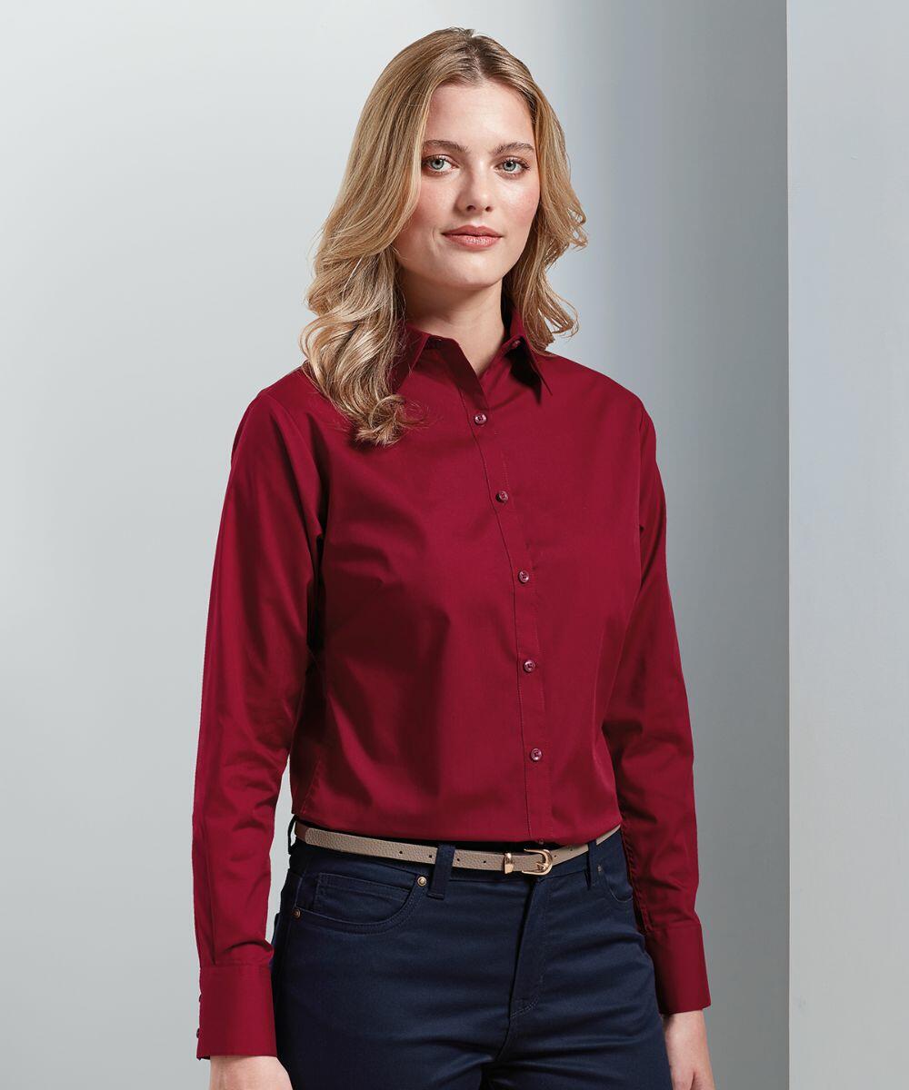A person with long blonde hair is wearing a red Premier PR300 button-down shirt and dark pants. They are standing against a plain light-colored background.