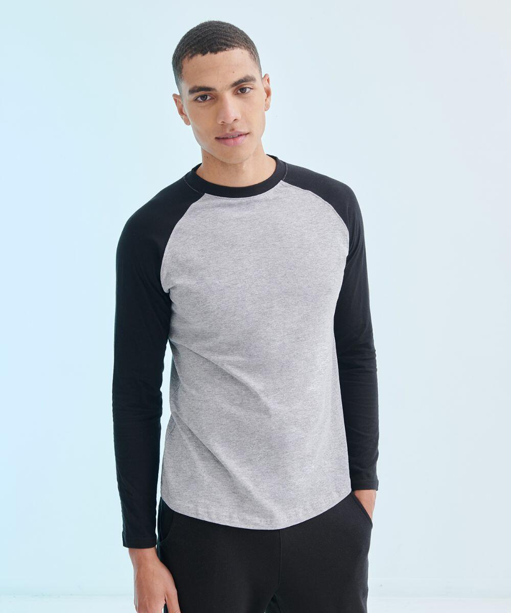 A person stands facing the camera, wearing an SF271 grey and black long-sleeve raglan shirt by SF and black pants. The background is plain and light-colored.