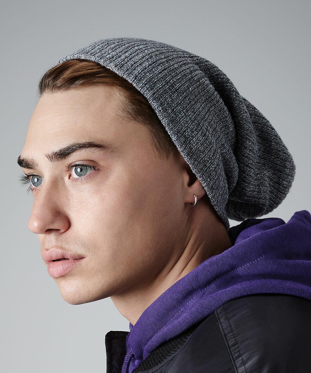 A profile image of a person with light-colored eyes, wearing a grey Beechfield BC449 beanie, a purple hoodie, and a black jacket. They have an earring in their left ear. The background is a simple grey, putting focus on the person's side profile.