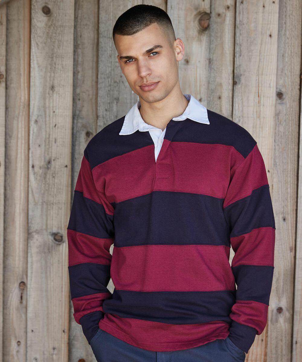 A person in a Front Row FR08M long-sleeved rugby shirt with horizontal maroon and navy stripes stands in front of a wooden wall.
