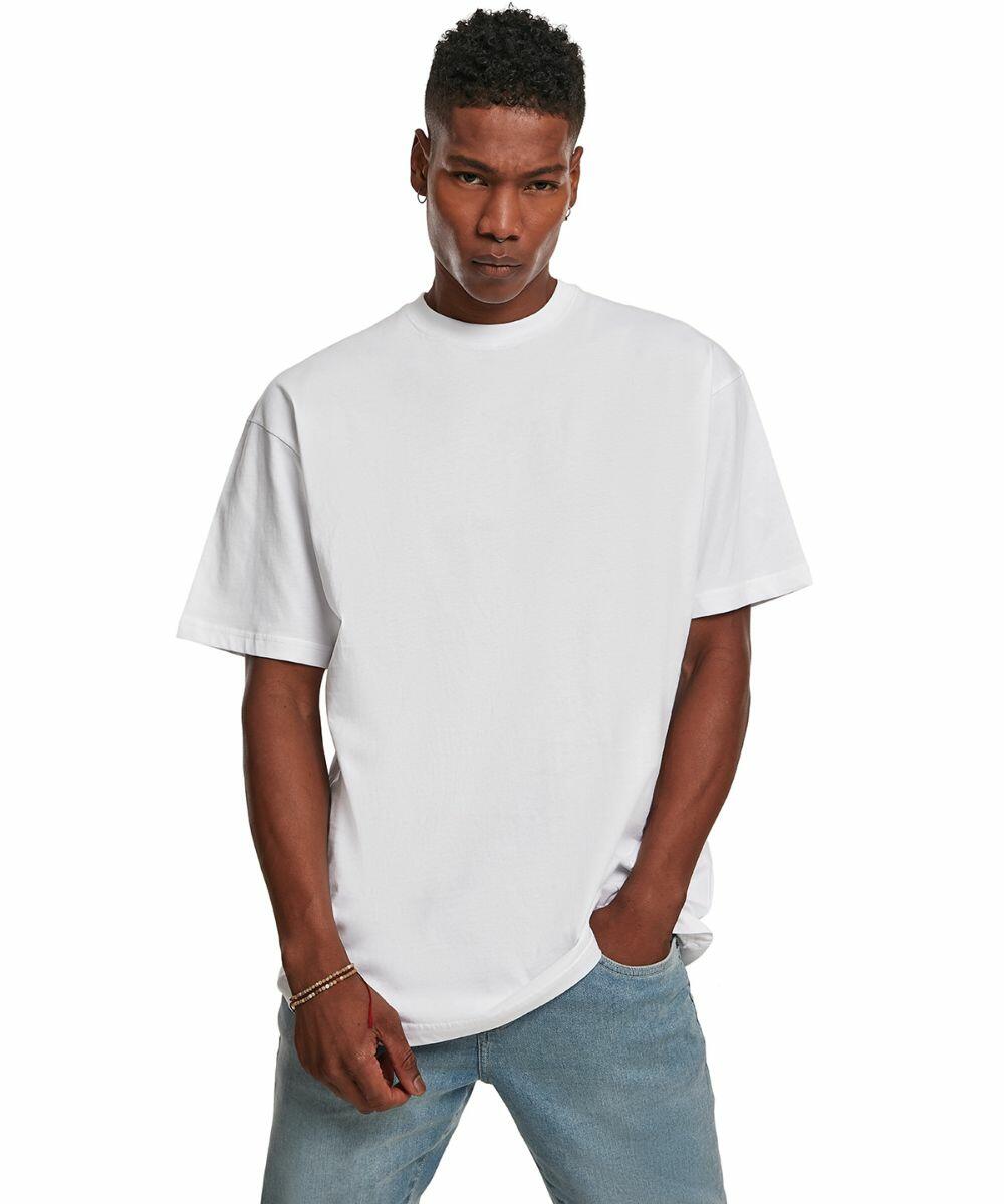 A person in a Build Your Brand BY122 T-shirt and blue jeans stands with one hand in a pocket, posing against a plain white background.