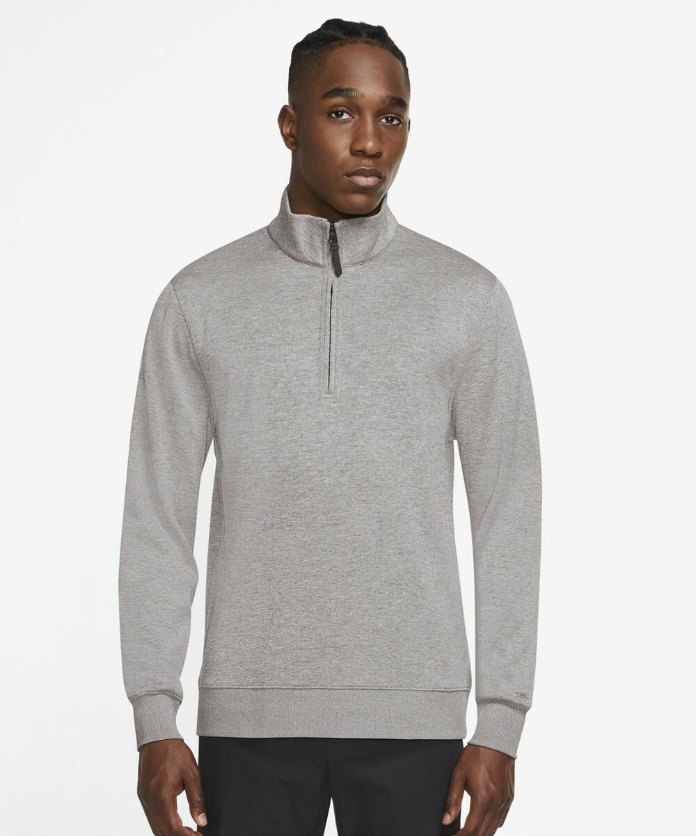 A person stands wearing a light gray Nike NK341 half-zip sweater and black pants, facing the camera.