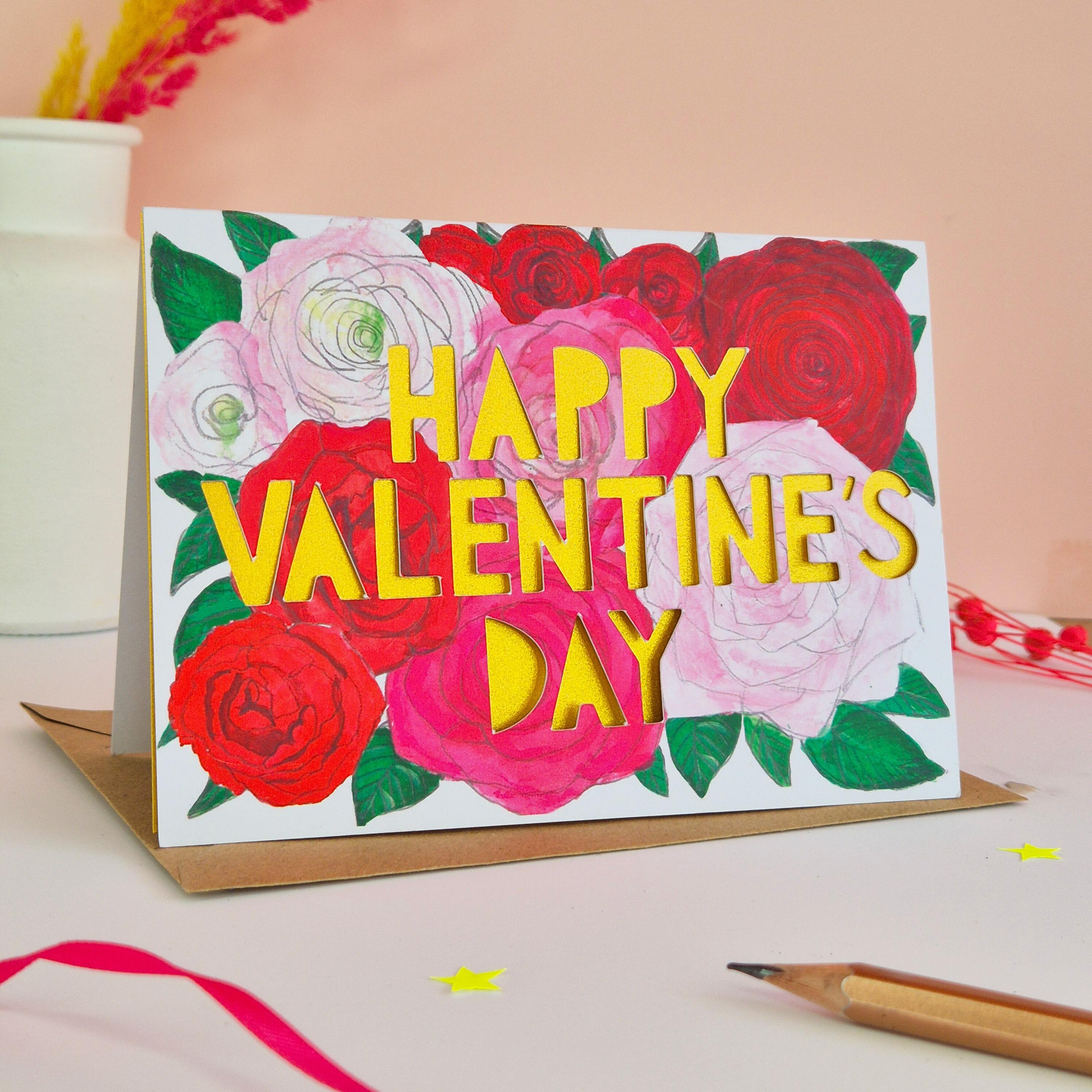 Romantic Valentine's Day card with pink and red flower illustrations, paper cut text and shimmering gold paper liner
