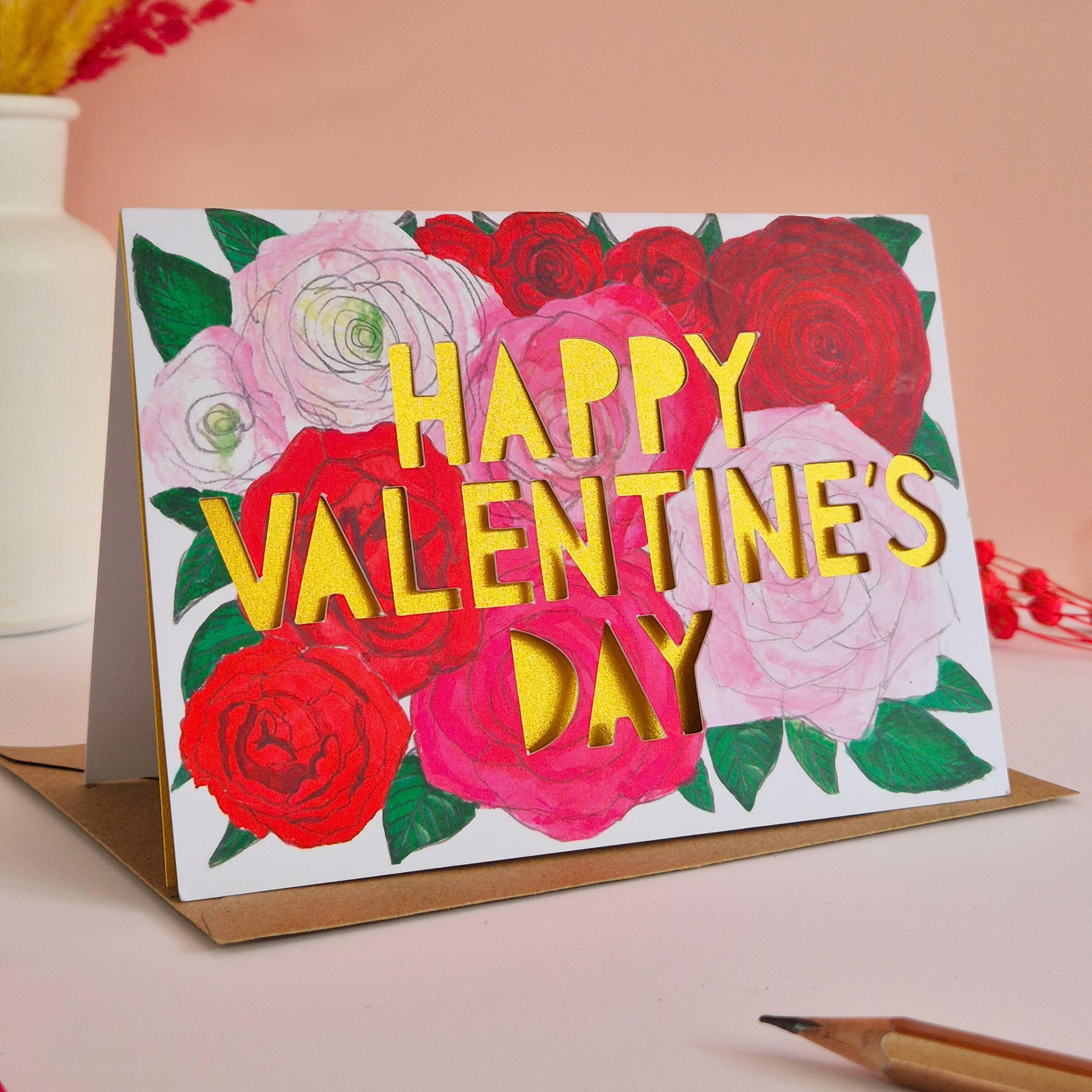 Romantic Valentine's Day card with pink and red flower illustrations, paper cut text and shimmering gold paper liner