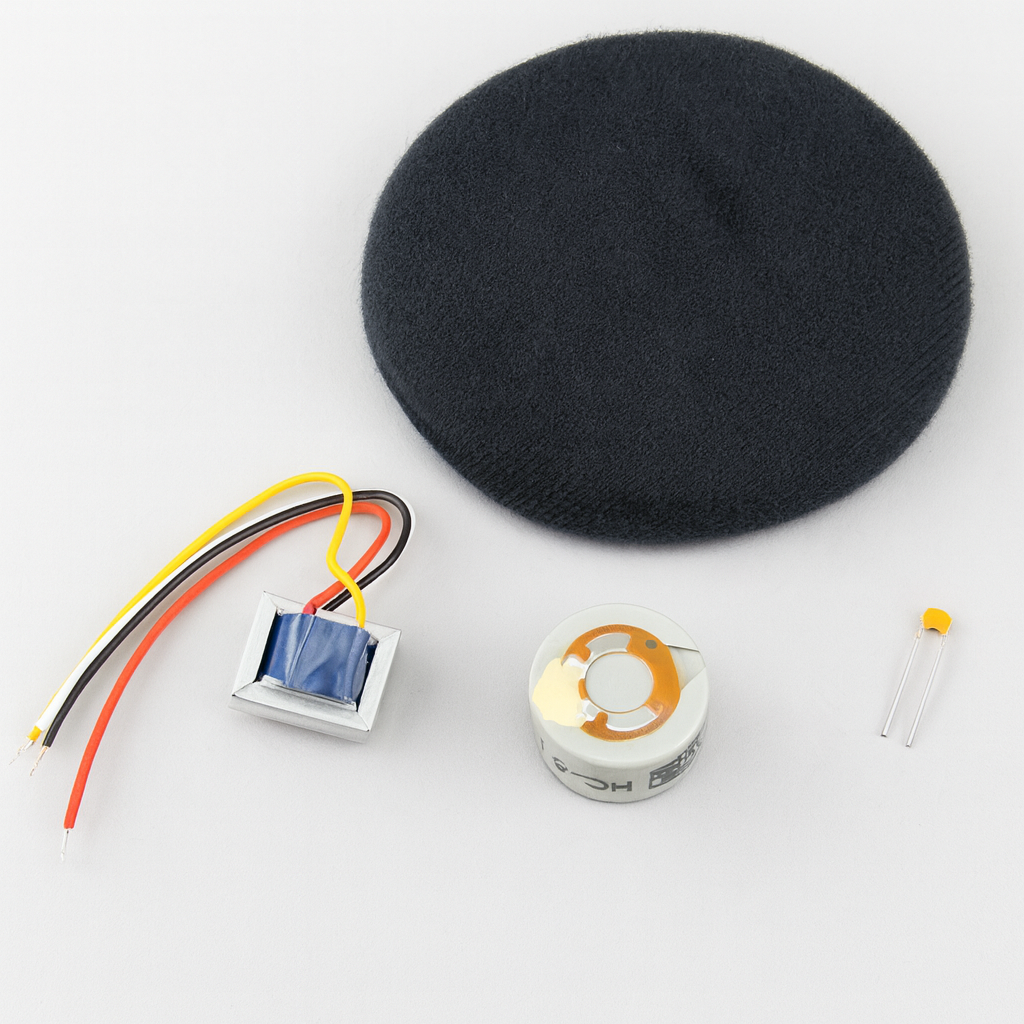 Electronic components including HC‑5.1 microphone capsule, transformer with wires, foam pad, and capacitor arranged on a light background.