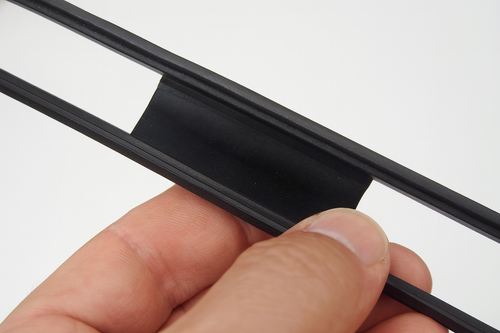 "Close-up of hand holding 450 Ohm ribbon feeder with black plastic spacer and twin-lead conductors against white background"