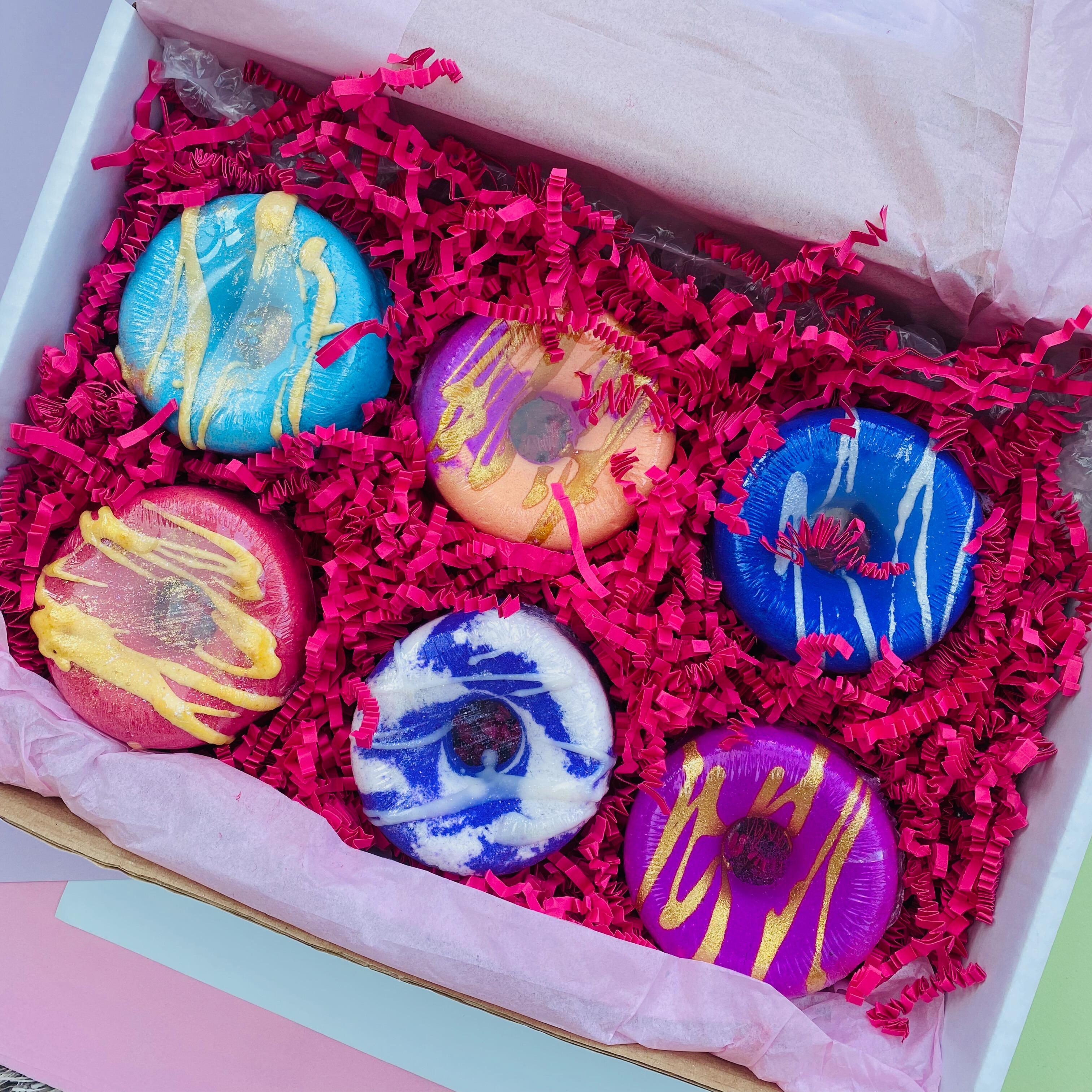 Top-down view of 6 colourful donut bath bombs in gift box