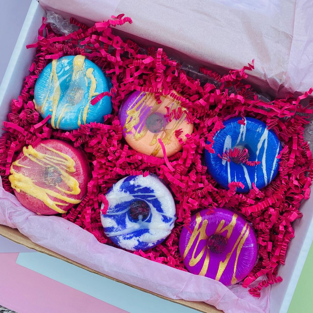 Top-down view of 6 colourful donut bath bombs in gift box