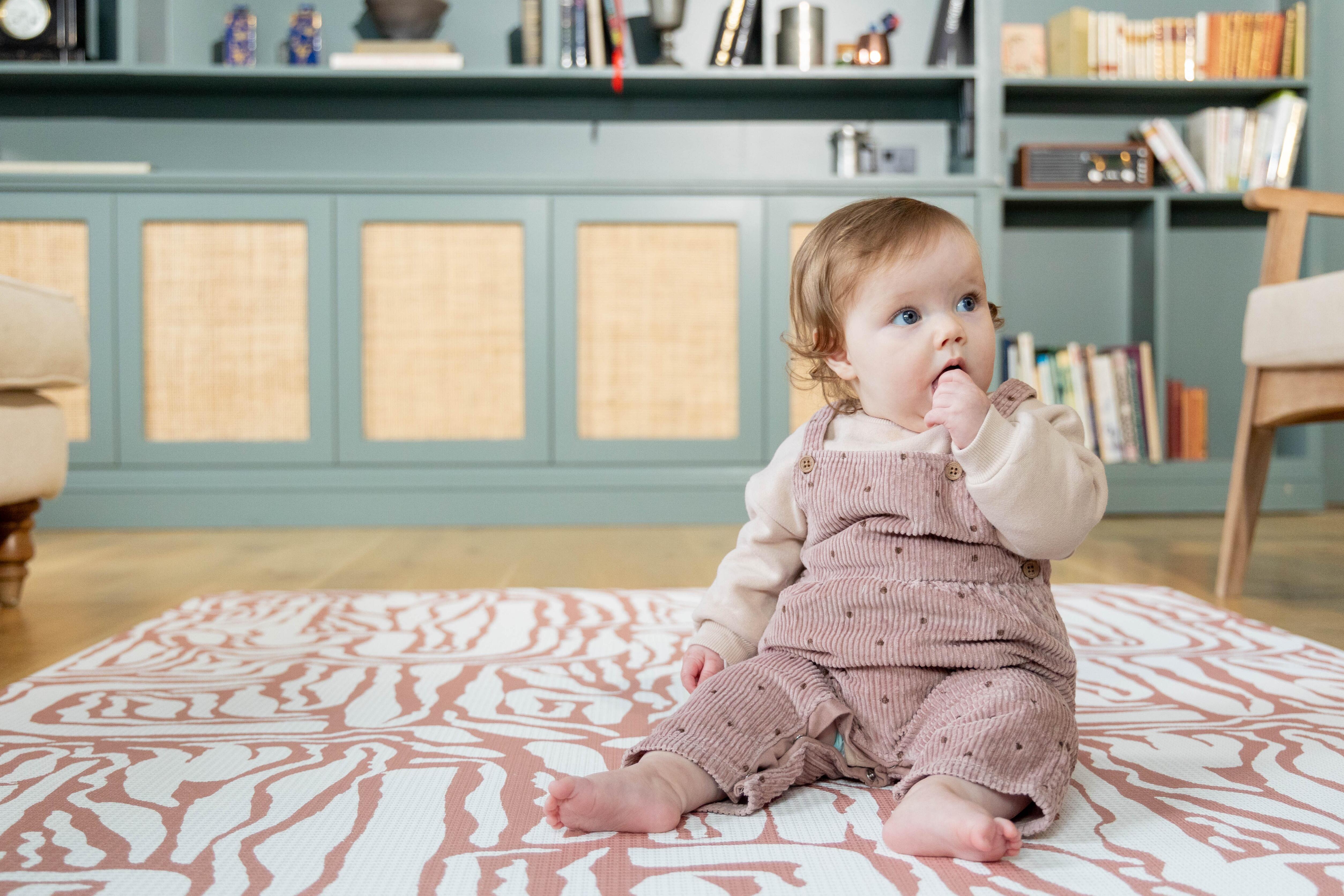 Baby sitting on Pathway Terracotta playmat – large reversible foam baby mat designed for stylish modern homes