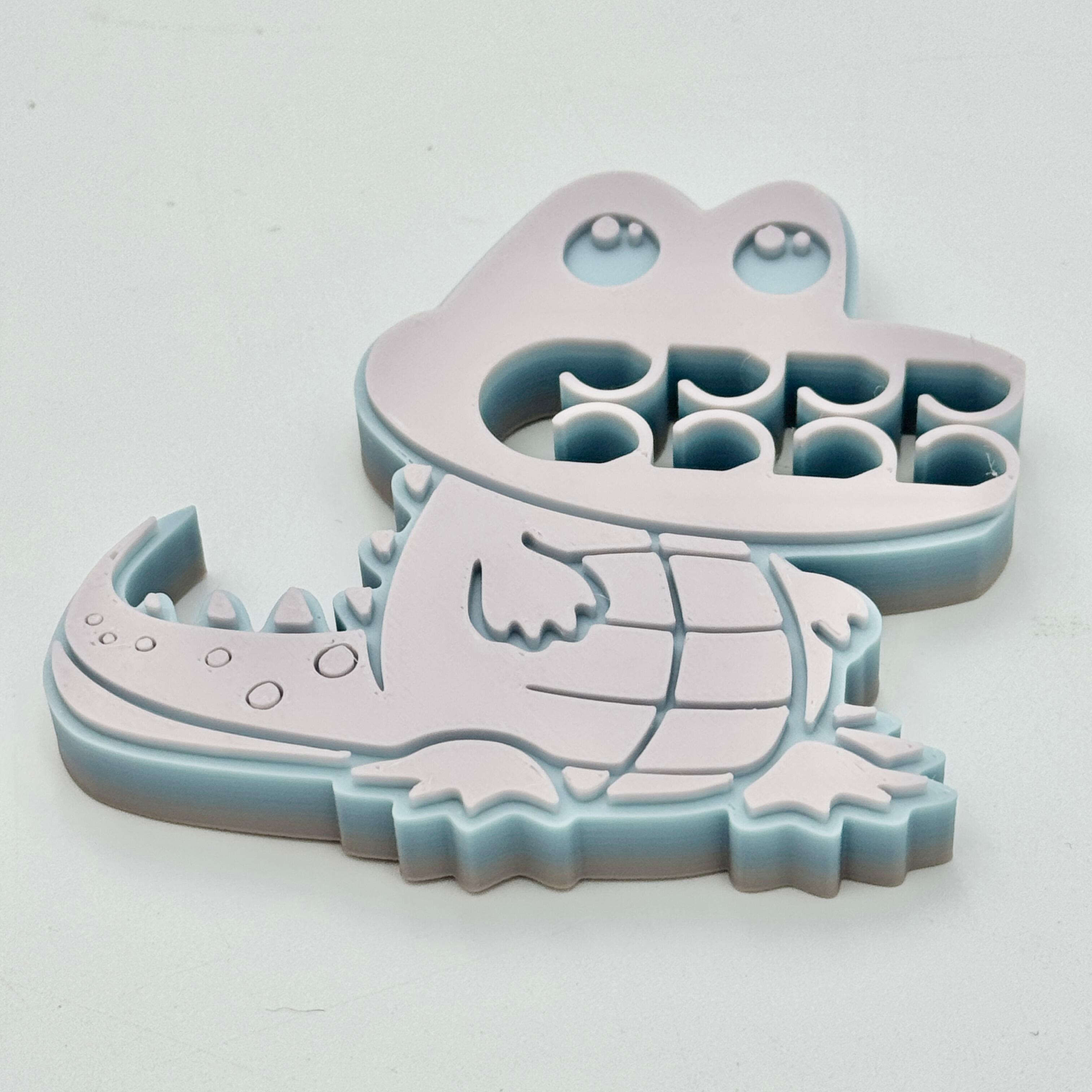 A grey, blue & pink crocodile bag clip
