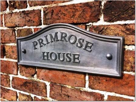 Picture of a humpback lead sign with the name Primrose House, lettering coloured black
