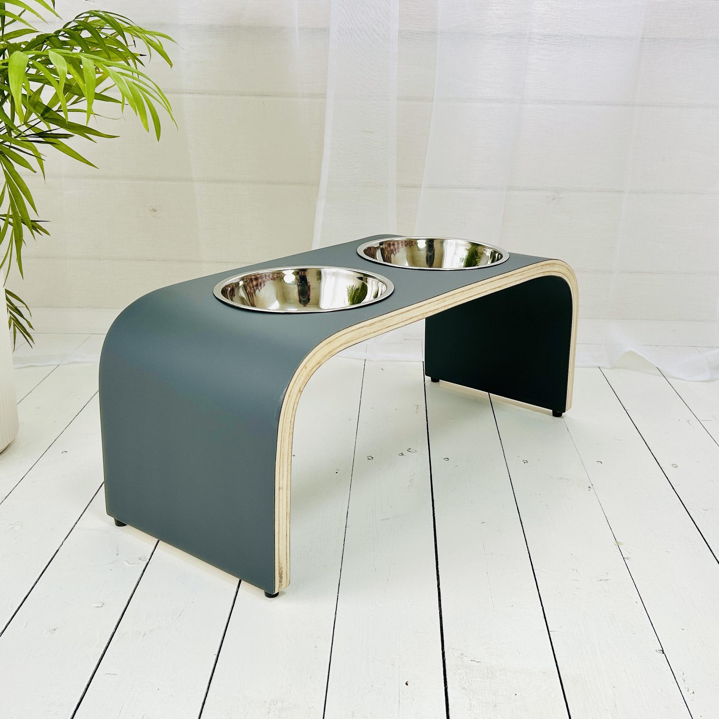 side angle view of matt dark grey dog feeding stand on white wooden floorboards