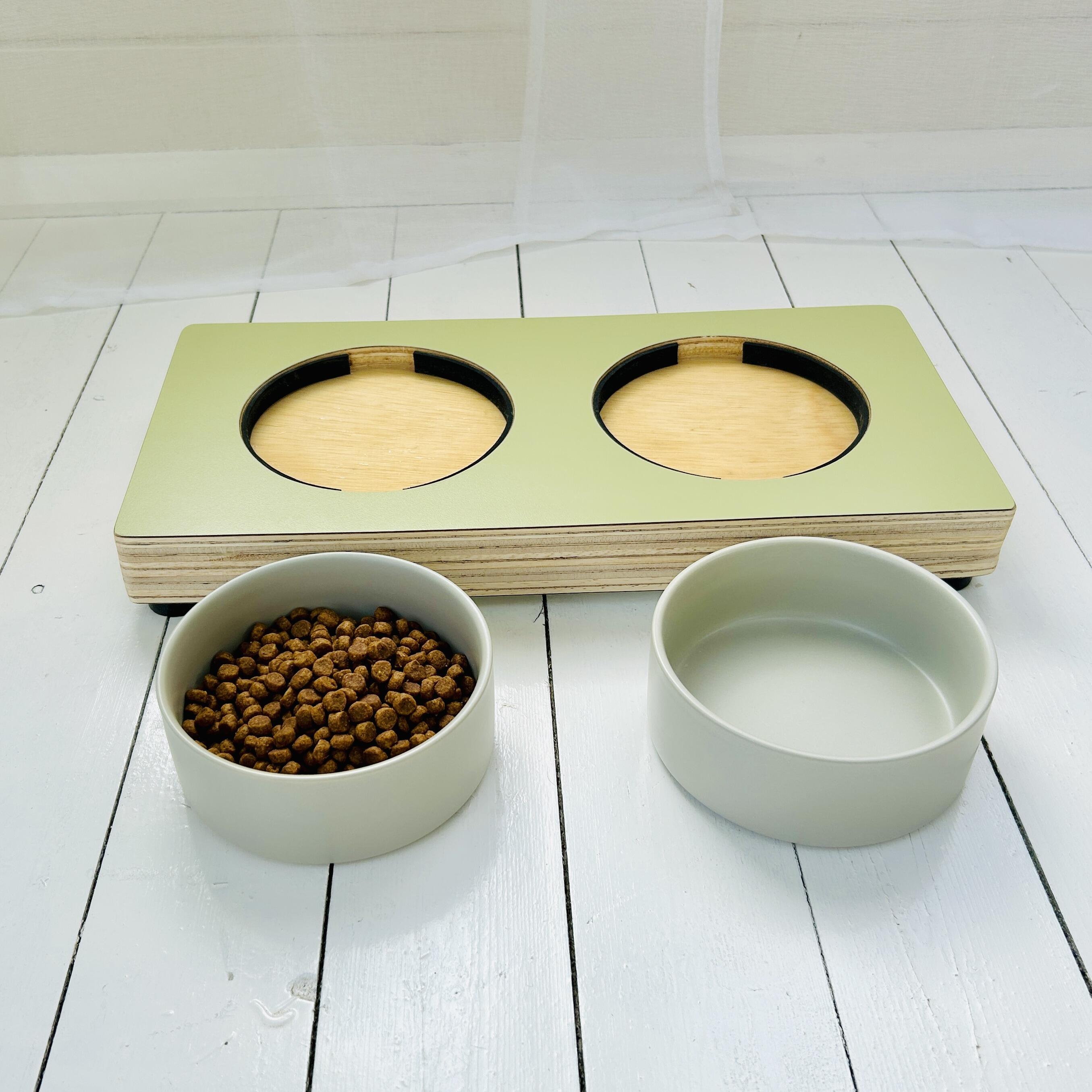 olive green wooden pet feeder showing bowl inserts with rubber padding and ceramic bowls in front