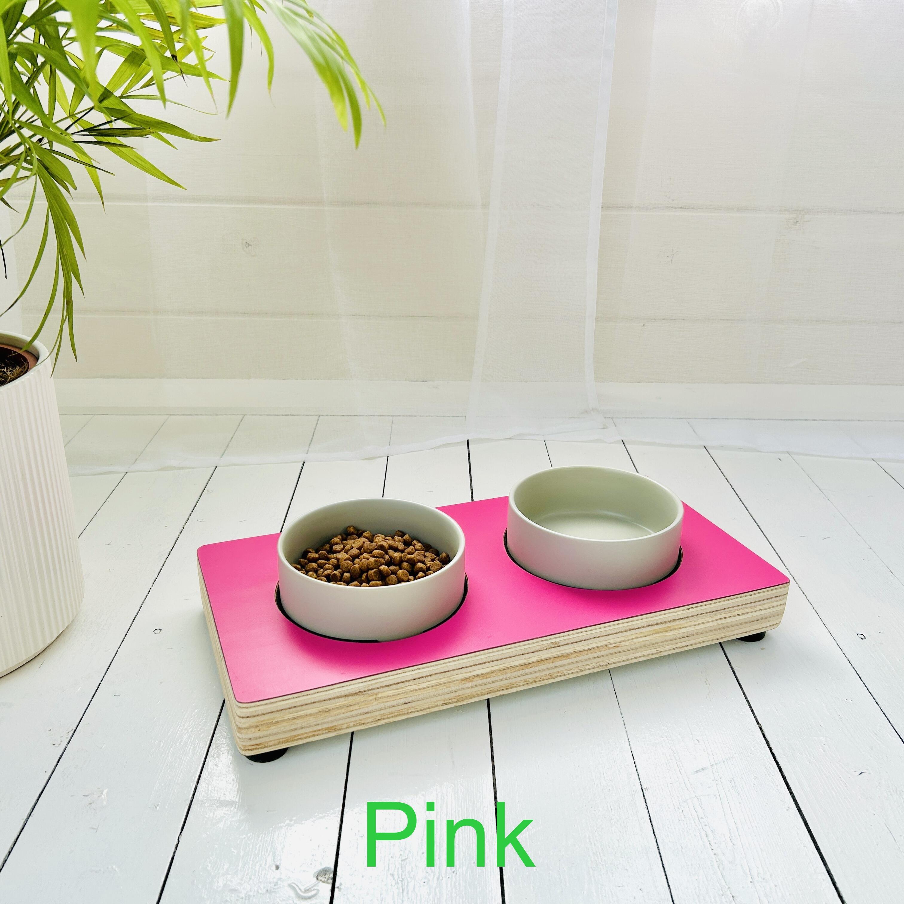 bright pink wooden cat bowl stand with ceramic bowls in white summer house setting