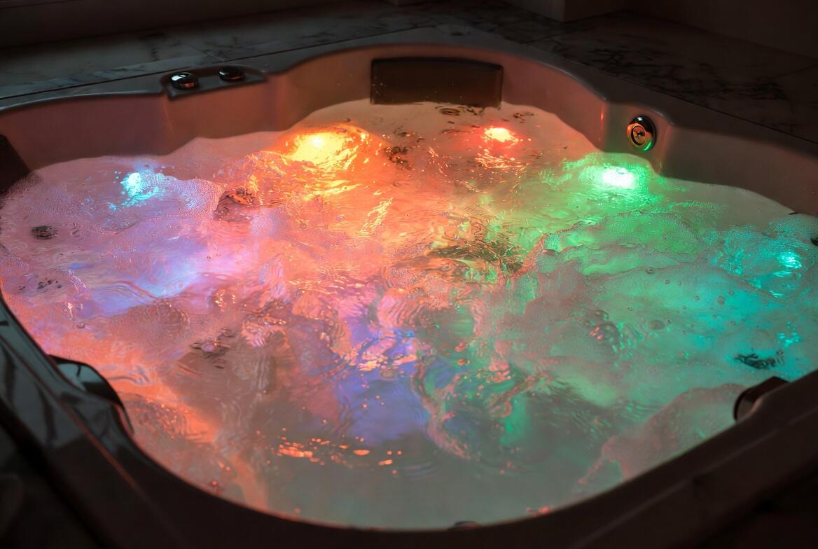 Close-up of underwater chromotherapy LED lights glowing in multiple colours inside a bubbling whirlpool bath