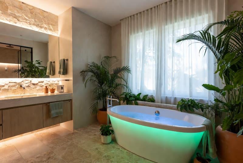 Modern luxurious bathroom showcasing 2026 trends with a whirlpool bath, natural biophilic elements, and layered smart lighting